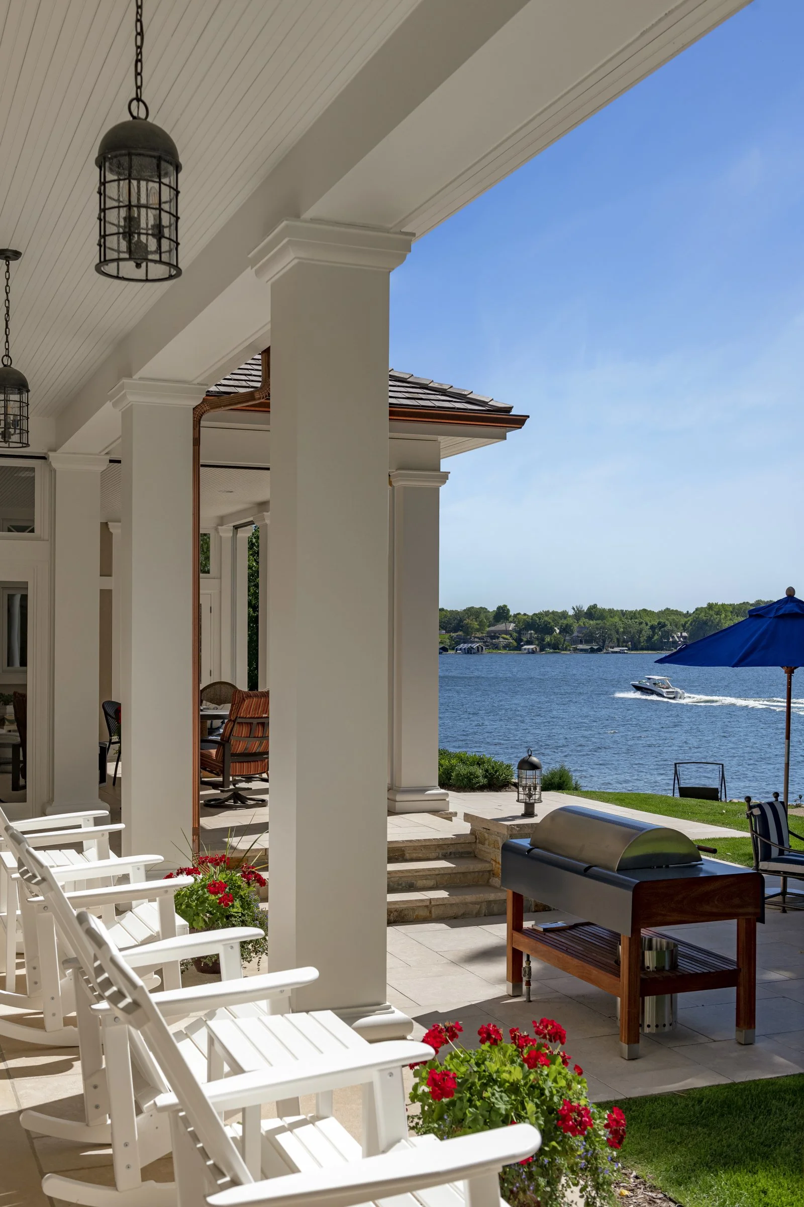 Lake house outdoor living, overlooking a view of the water with a boat passing by.