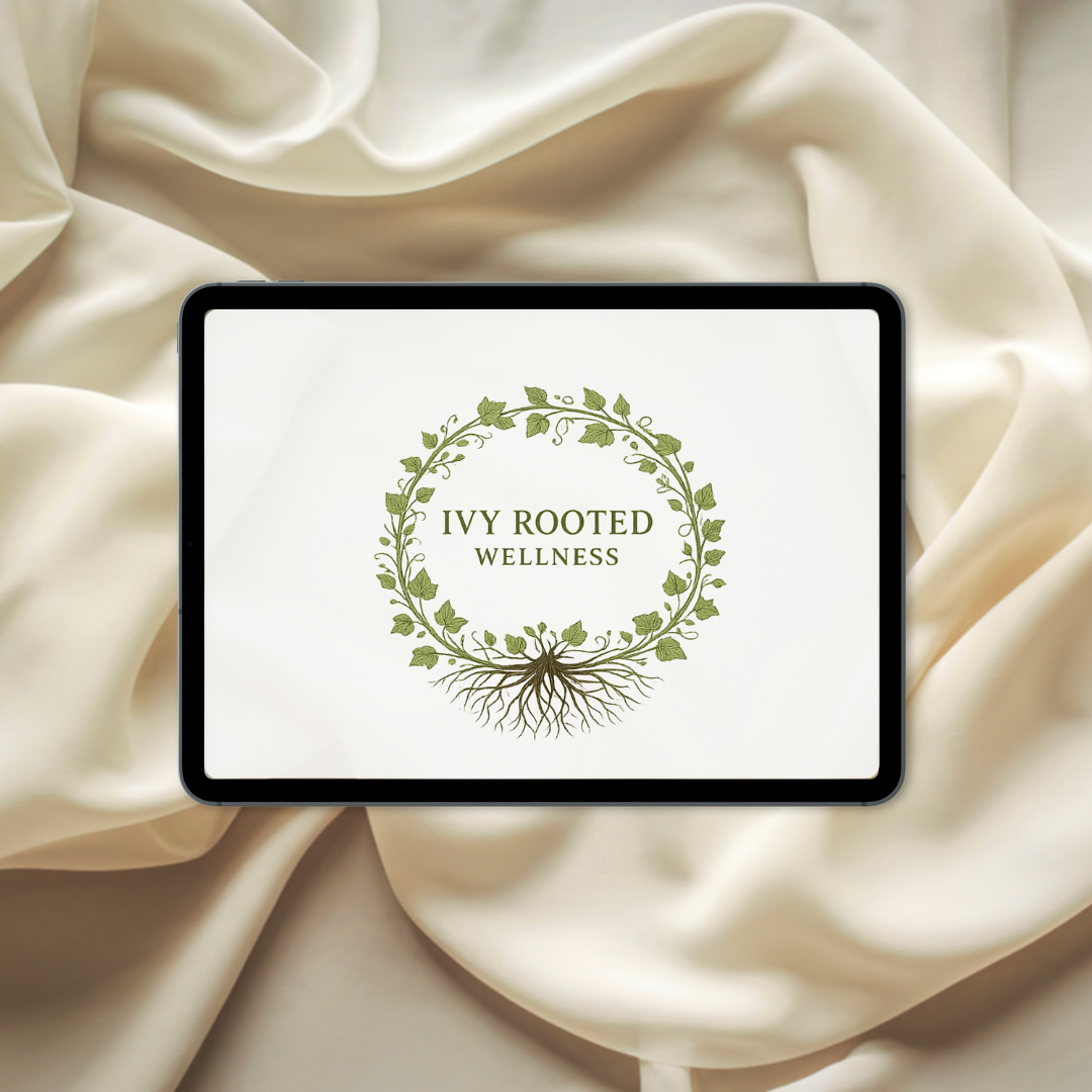 An iPad displaying a logo for Ivy Rooted Wellness, featuring a circular vine with leaves and roots, placed on ivory satin fabric.
