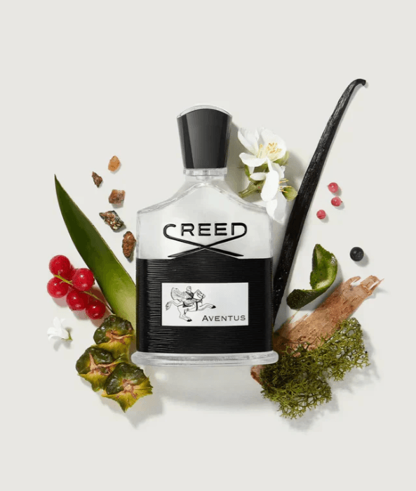 A bottle of Creed Aventus cologne  surrounded by natural elements like berries, green leafy plants, a white flower, a vanilla bean, and moss. Click on image to buy. NEED HELP OR NEED A RETURN? CONTACT US BY FILLING OUT THE FORM ON THIS PAGE!