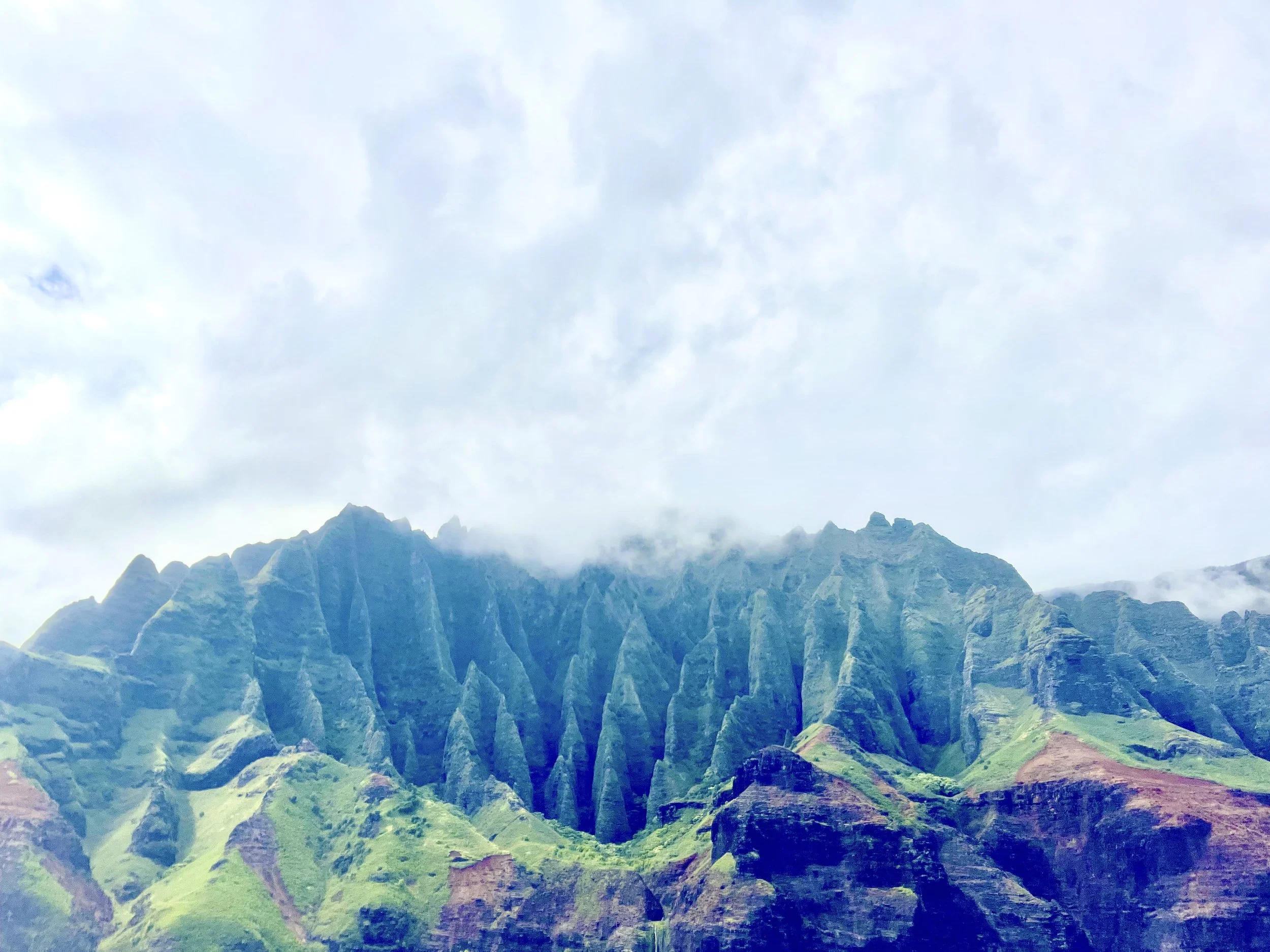 A colorful painting of a mountain landscape with peaks, valleys, and green areas under a cloudy sky.