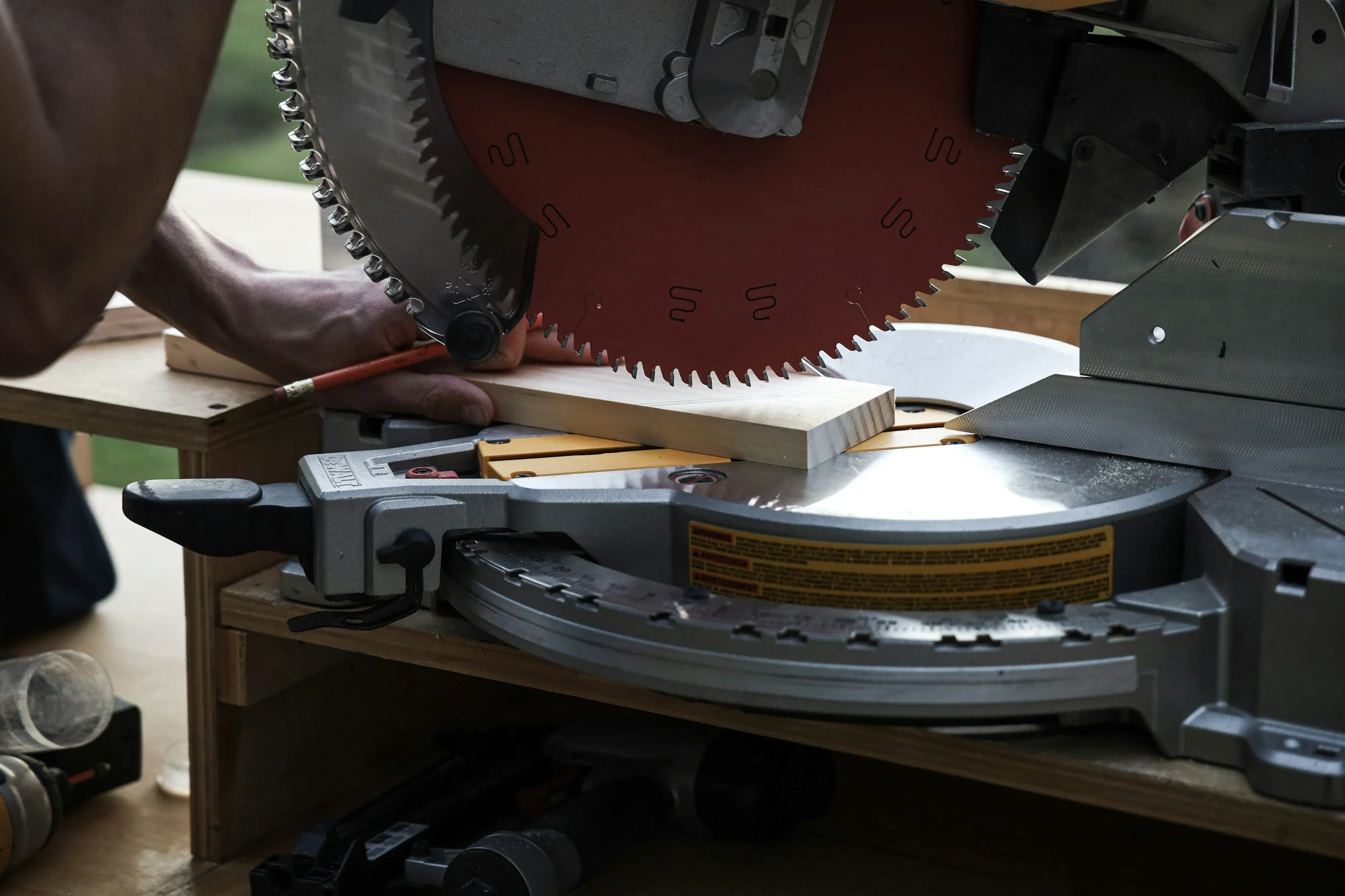 A person operating a miter saw to cut a wooden board during a woodworking project.