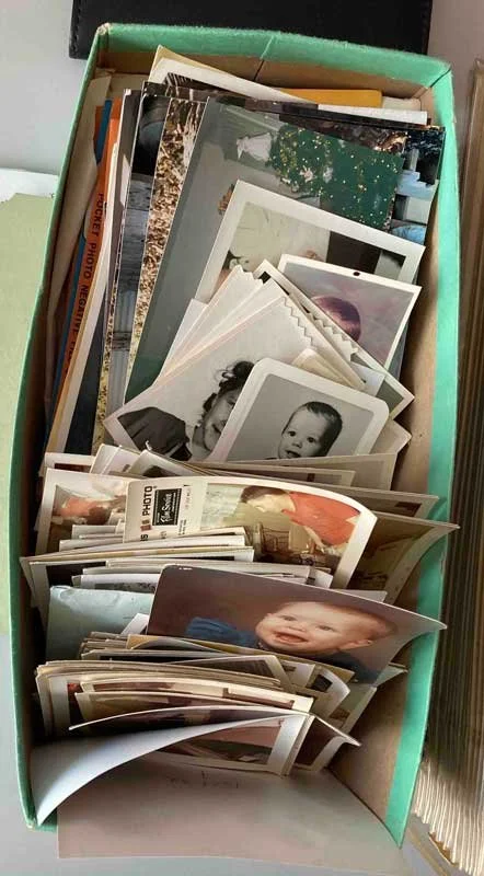 A shoebox full of old family print photos waiting to be digitized.