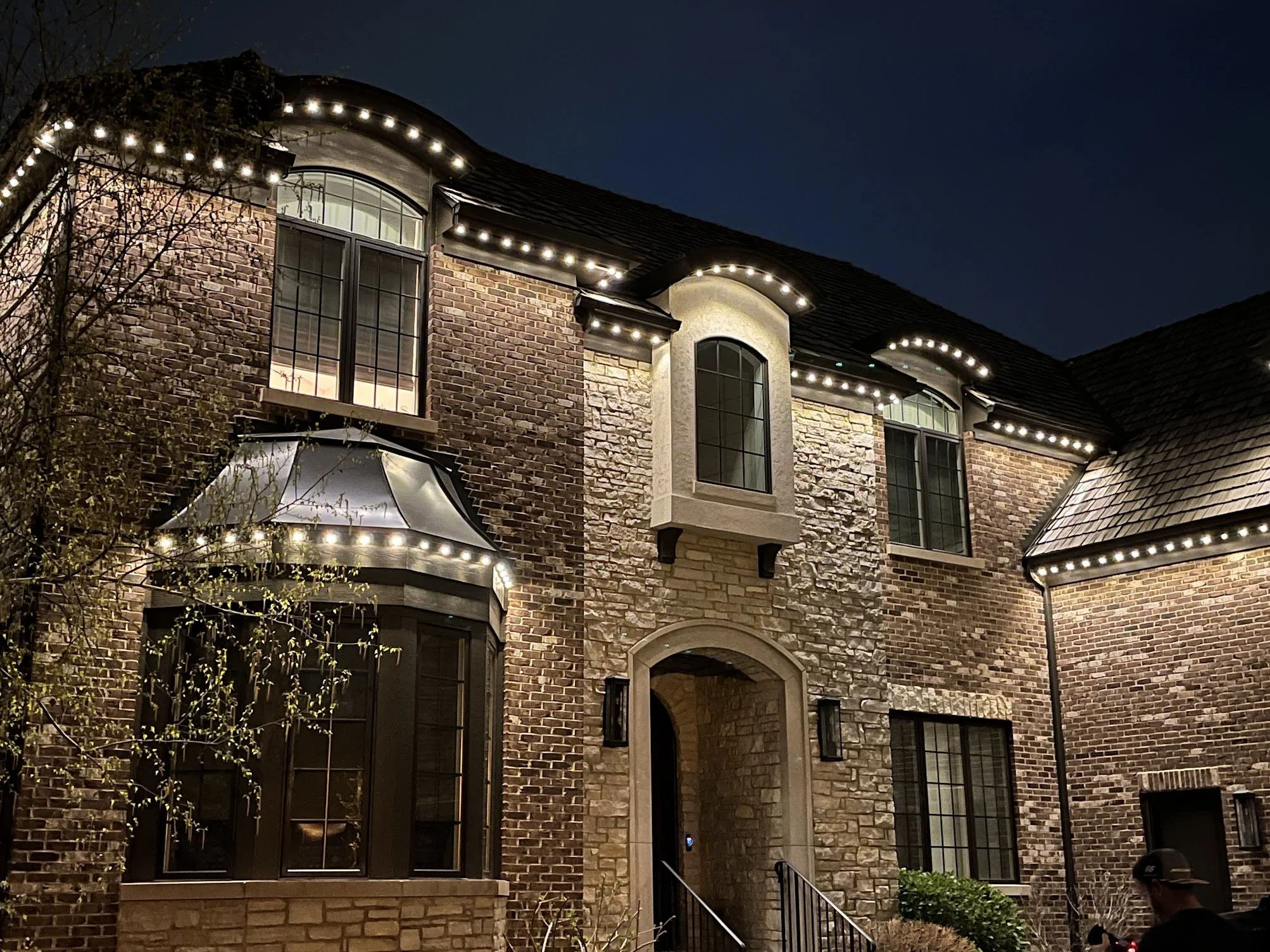Exterior of a modern house decorated with colorful string lights at night.