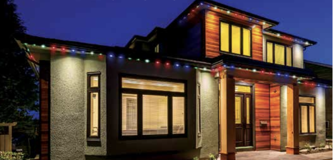 A modern house decorated with colorful Christmas lights at night.