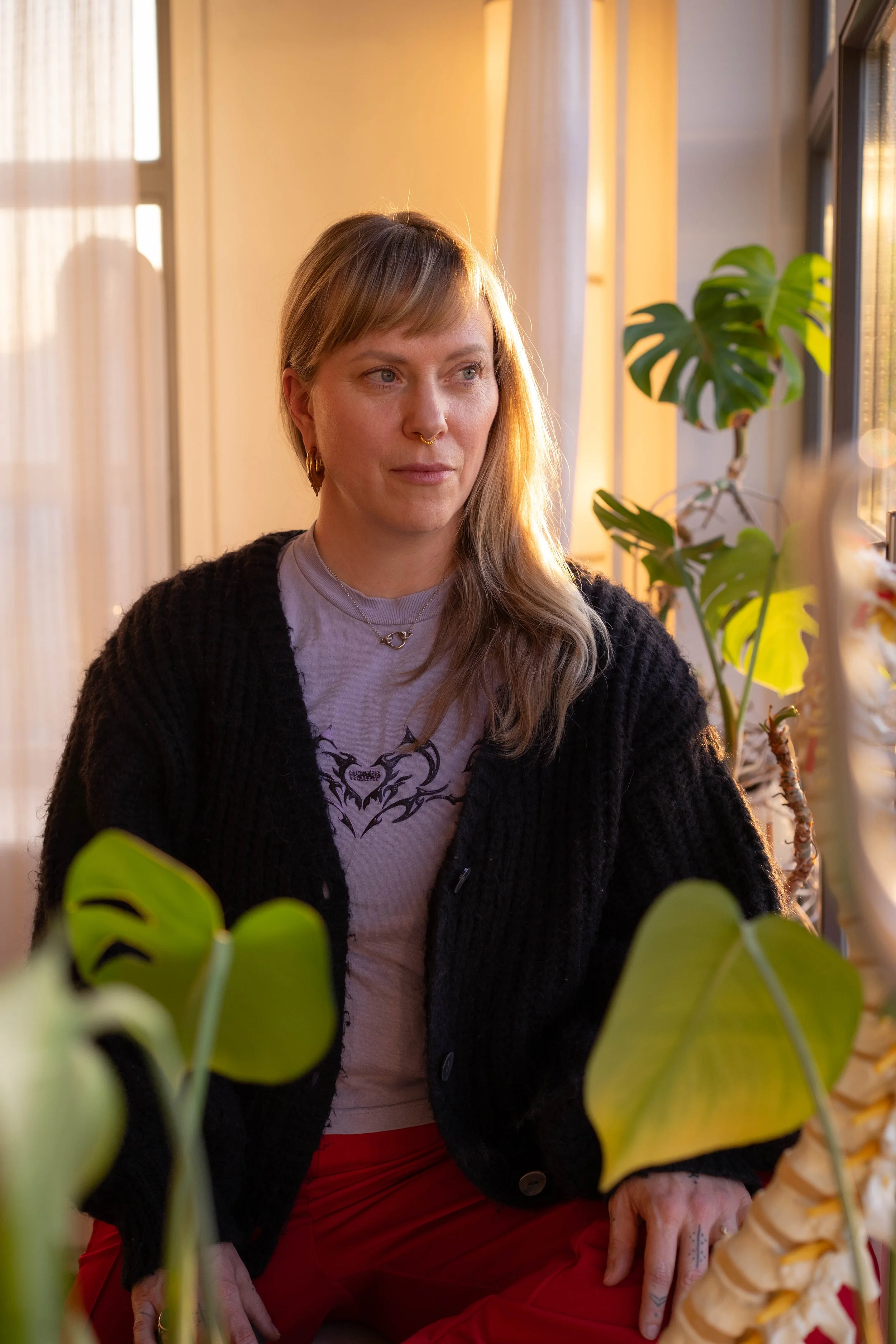 Portræt af Evaloa - omgivet af grønne planter, og ser tænksom ud i det varme lys.