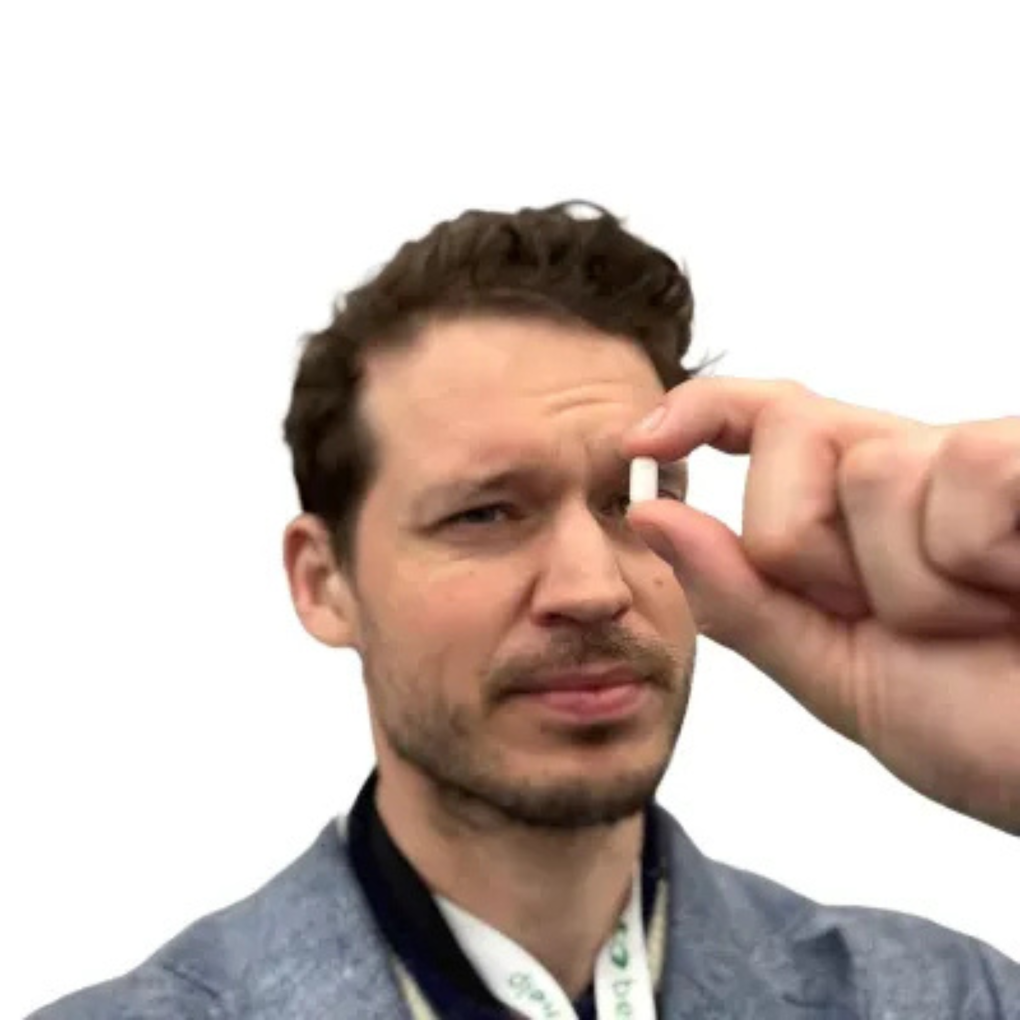 Billedet viser Billedet viser Anders Sørensens Spotify foto:  Et nærbillede af en ung mand med brunt, kort, bølget hår iført en grå jakke og hvid skjorte, der undersøger en pille mellem sine fingre.