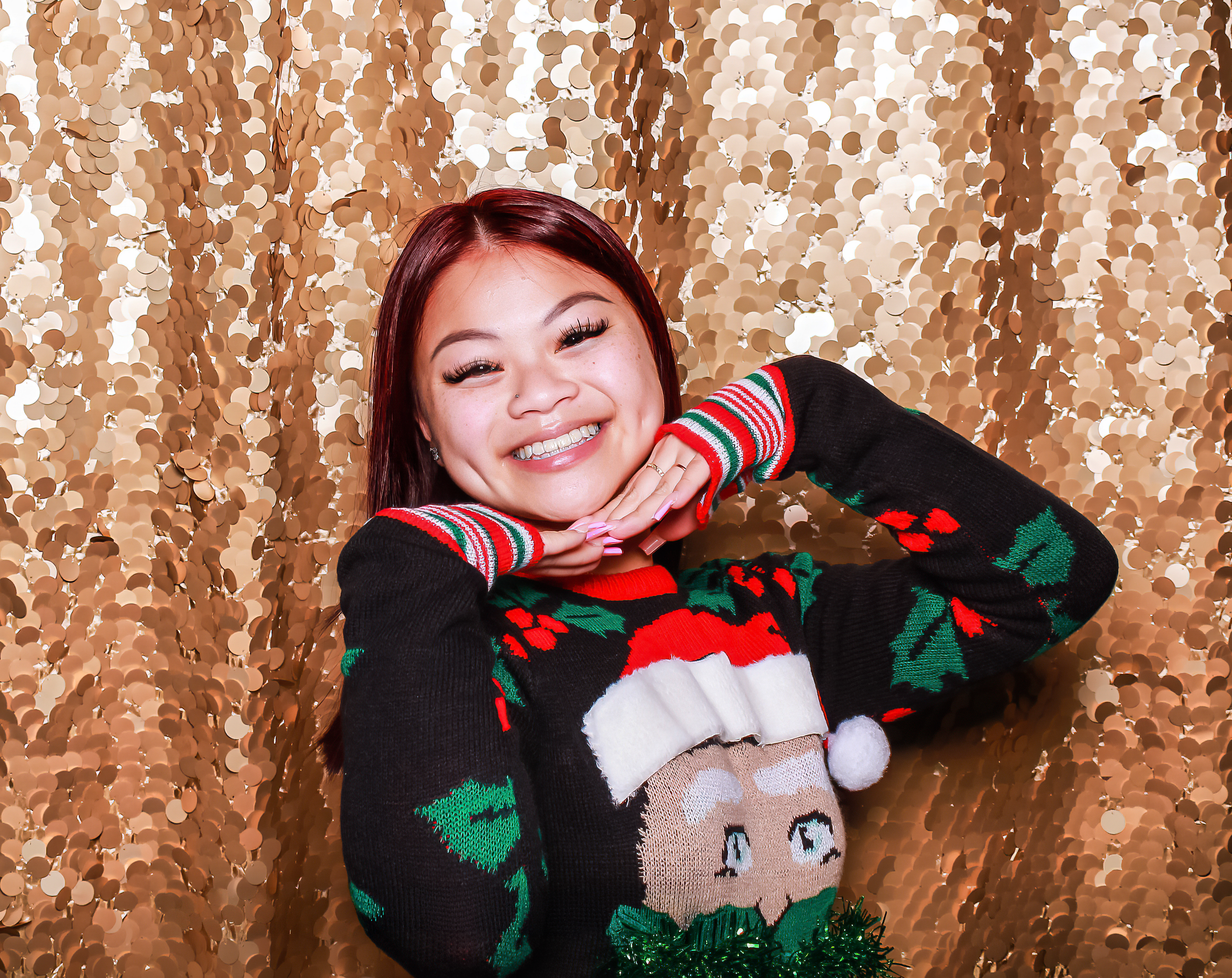 Smiling Asian woman posing in front of a gold backdrop at a photo booth event.