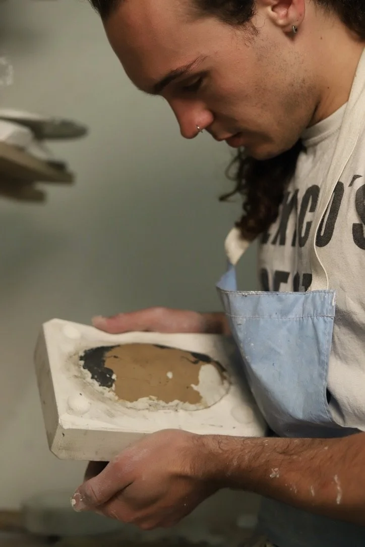 Person looking closely at a ceramic piece held in both hands, with a focus on the ceramic's surface.
