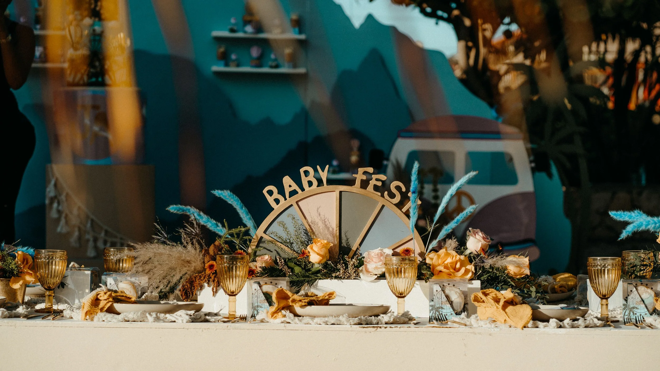Table decorated with floral arrangements, candles, and a sign that reads 'Baby Fes'.