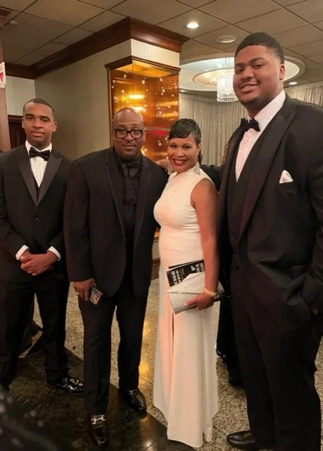 Brisa Builders Corp. Four people dressed in formal attire posing together at a banquet hall.