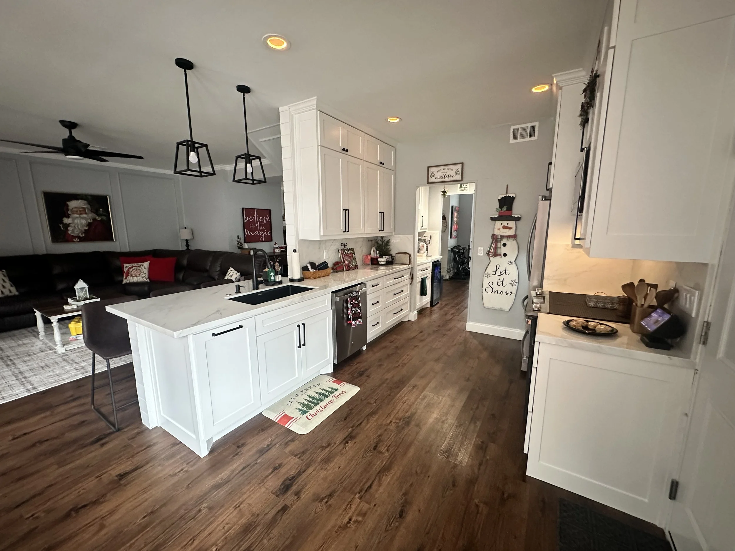 Renovated open-concept kitchen and living room with white cabinets, and wooden floors