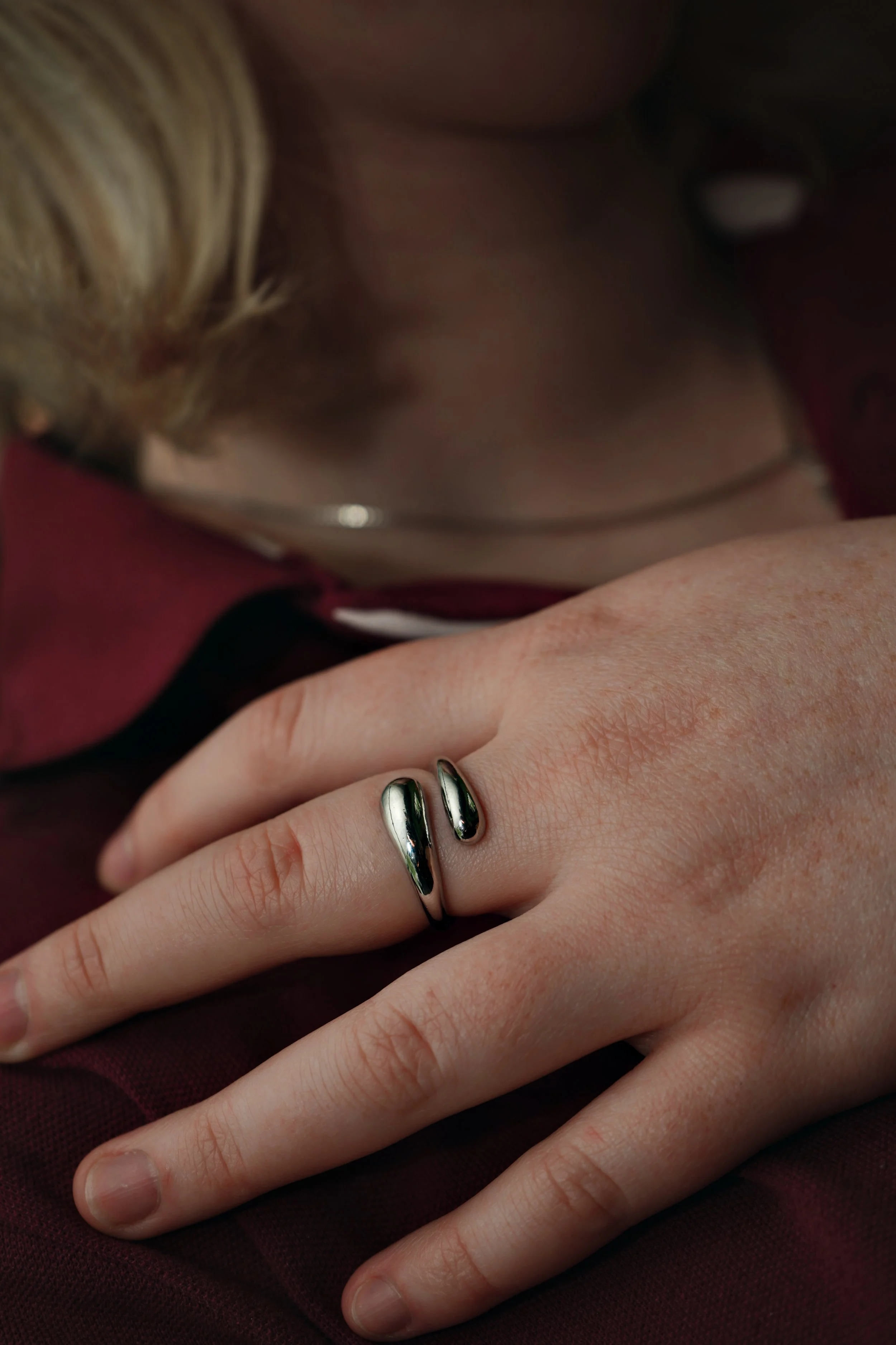 Nærbillede af en hånd med en sølv ring på pegefingeren, hvor baggrunden er mørk og forvirret.