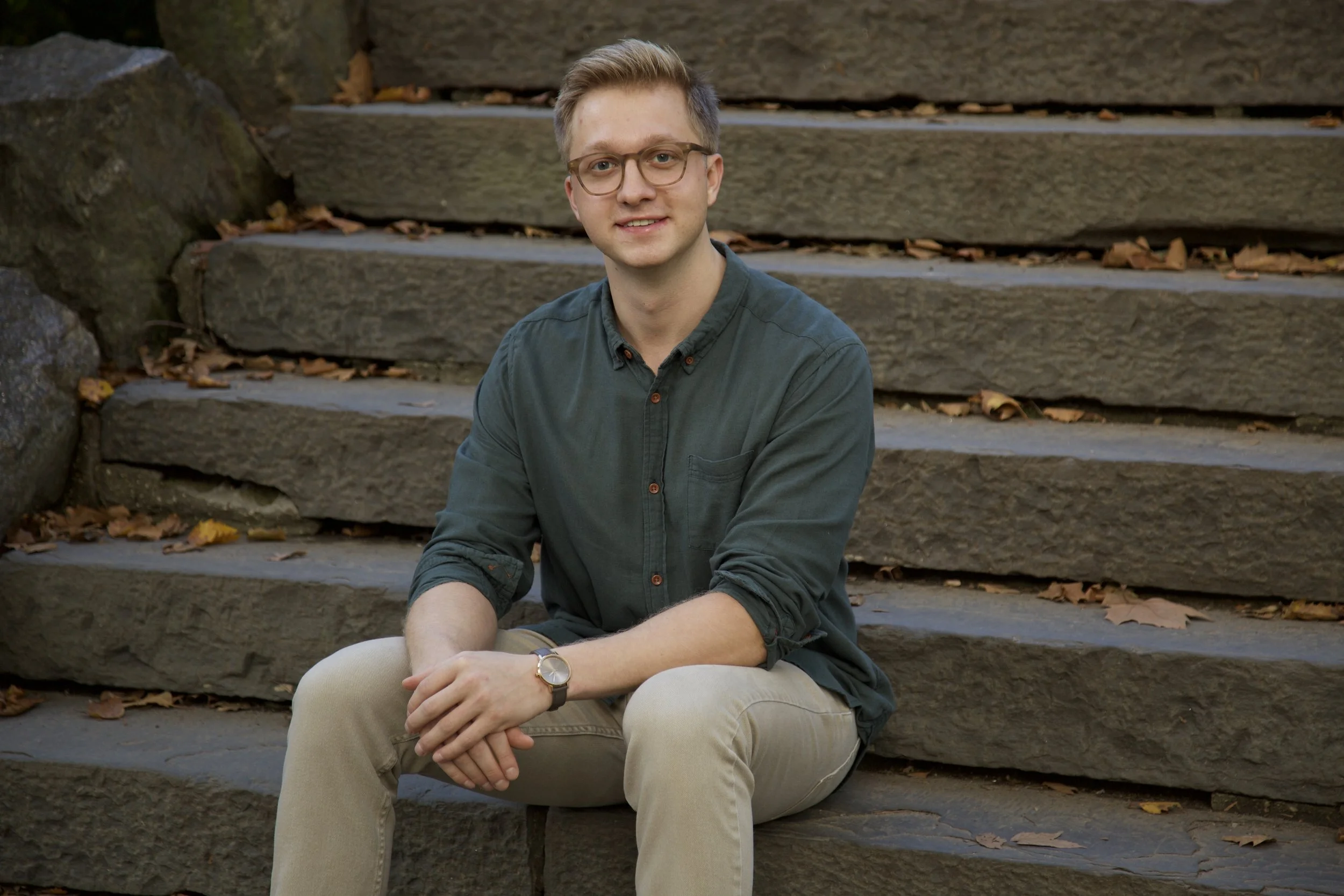 Jack Szary, LMHC-D, therapist at Rhythm Wellness, seated outdoors on stone steps