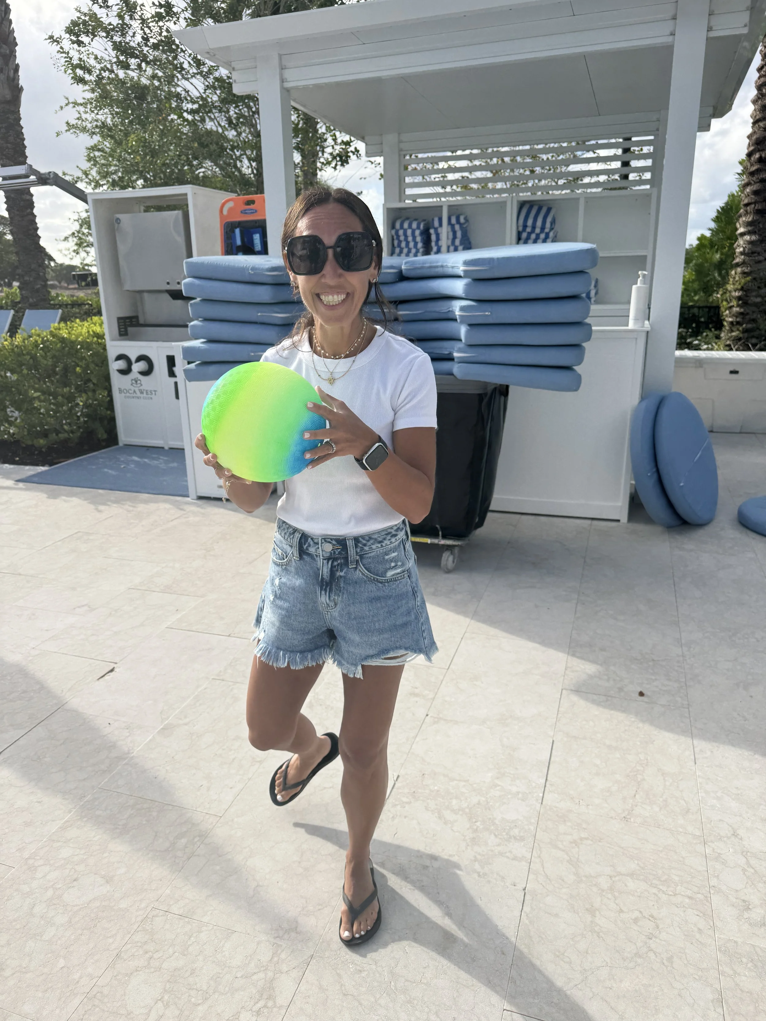 Lindsay Levine smiling and holding a colorful ball on a sunny beach day