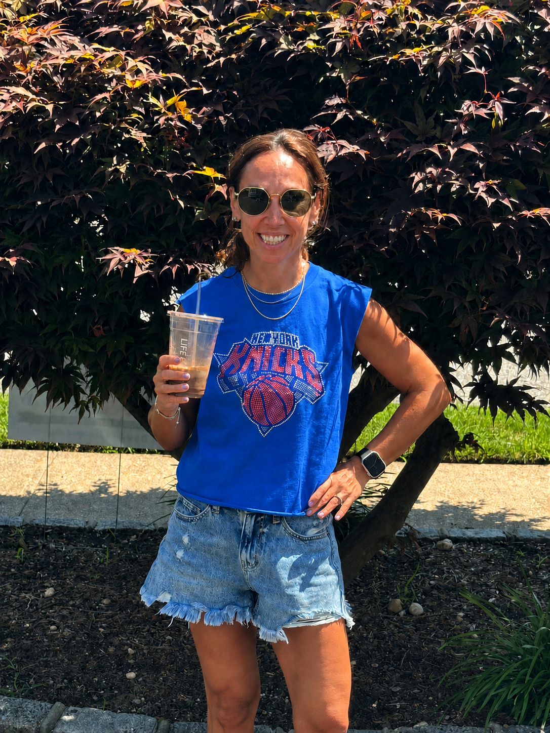 Lindsay Levine smiling and holding an iced coffee on a day
