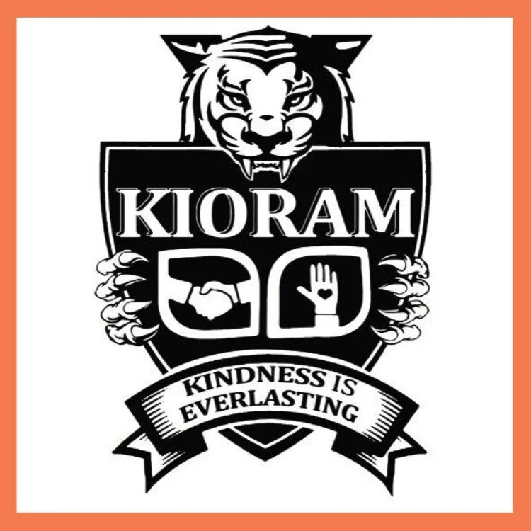 A logo featuring a fierce-looking lion's head above a shield. The shield contains the text 'KIORAM' and symbols of a handshake and a hand with a heart. Below, a banner reads 'Kindness is Everlasting'.