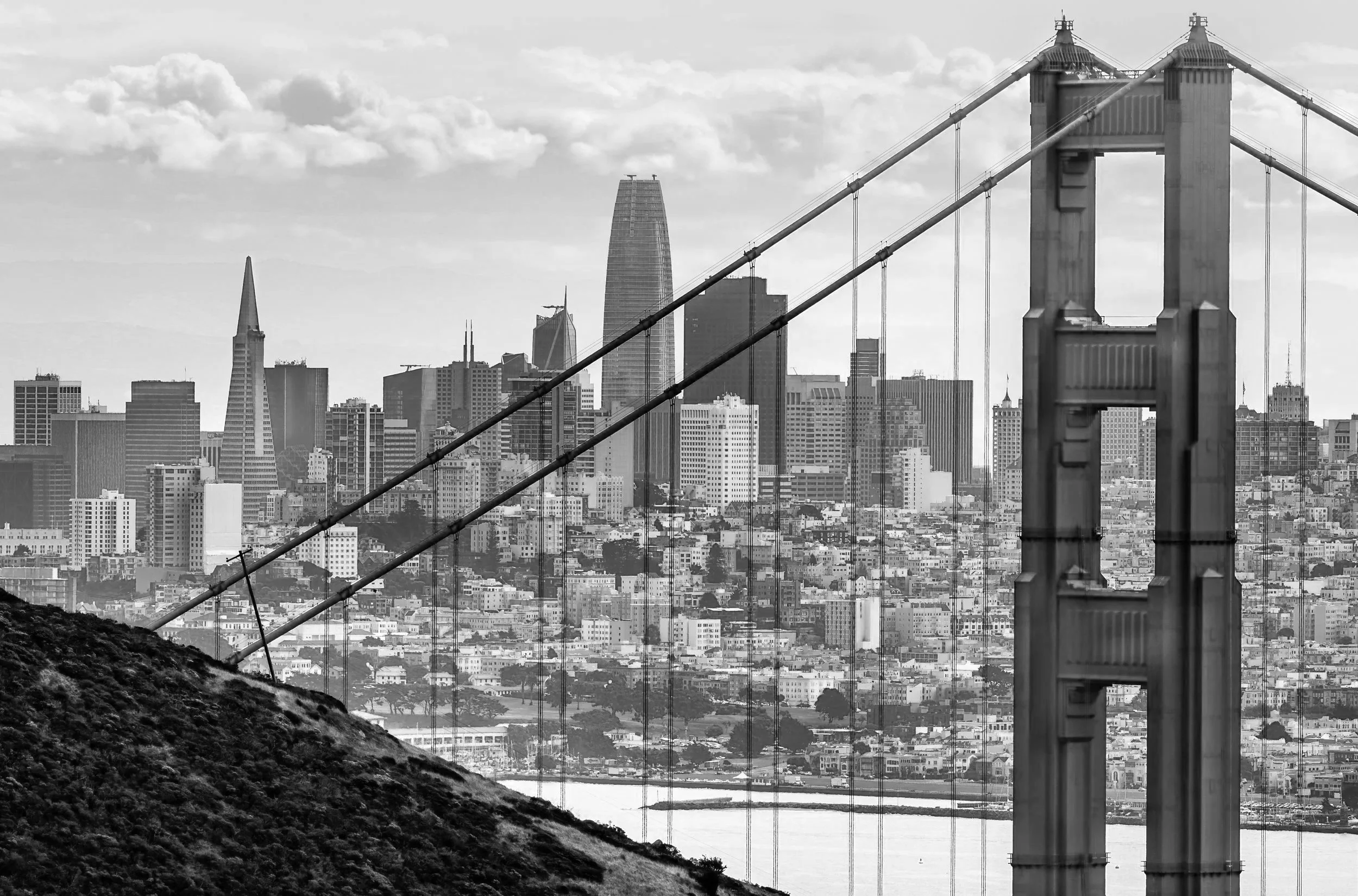 Black and white photo of San Francisco skyline with Golden Gate Bridge in the foreground and city buildings in the background.