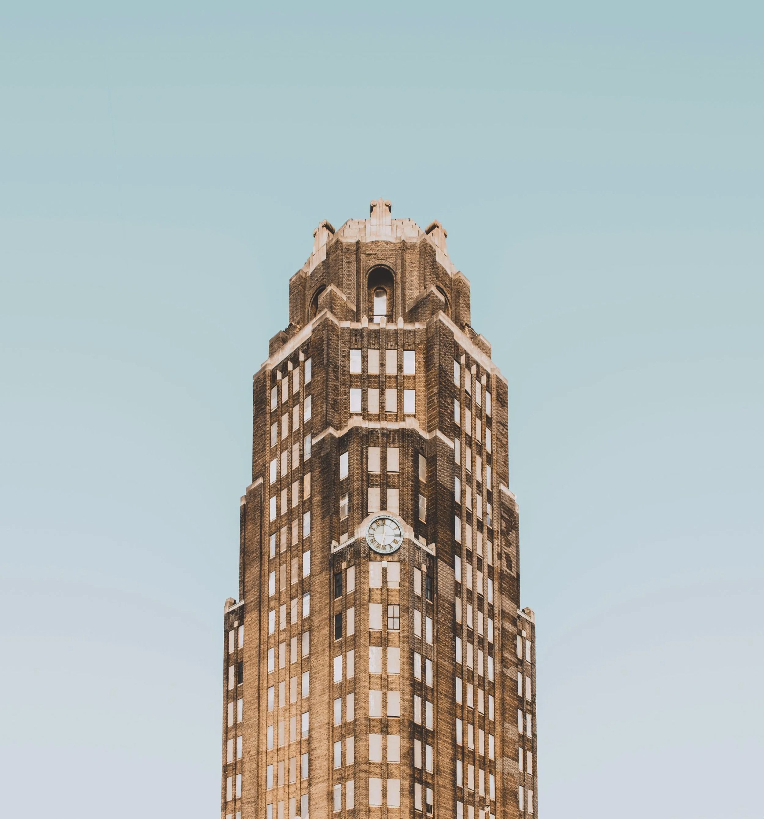 A tall historic skyscraper with a clock on its facade, set against a clear blue sky.