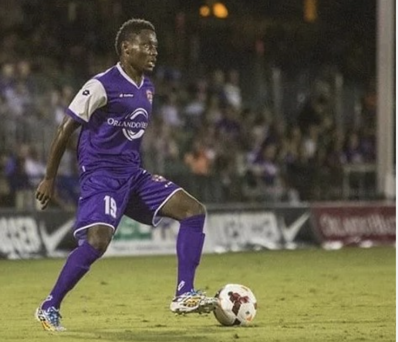 Soccer player in purple uniform with number 15 on field about to kick soccer ball at night.