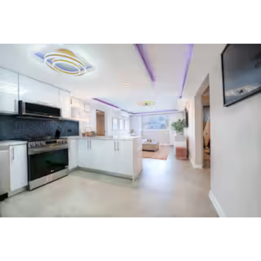 Bright, modern open-concept kitchen with white cabinets, stainless steel appliances, and purple LED lighting accents.