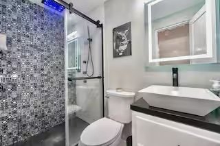 Modern bathroom with a walk-in shower, white toilet, and a vanity with a vessel sink