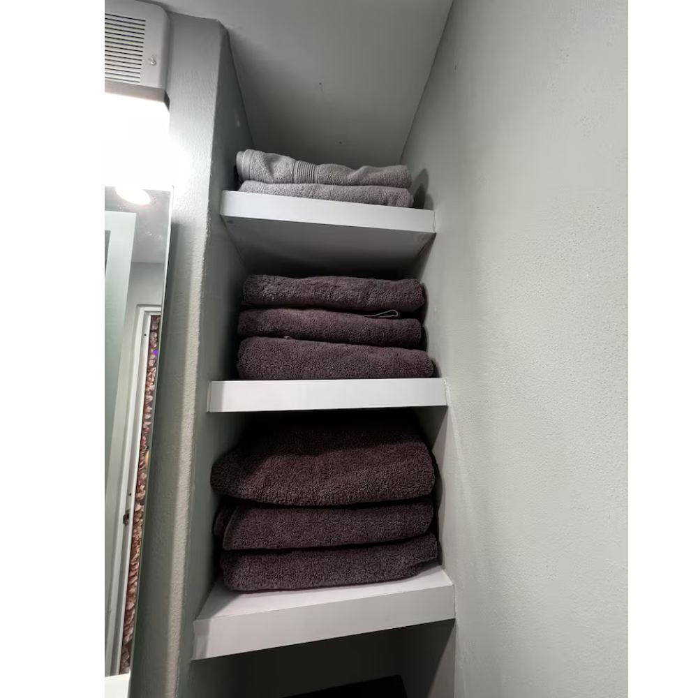 Shelves with folded gray and dark gray towels in a bathroom.