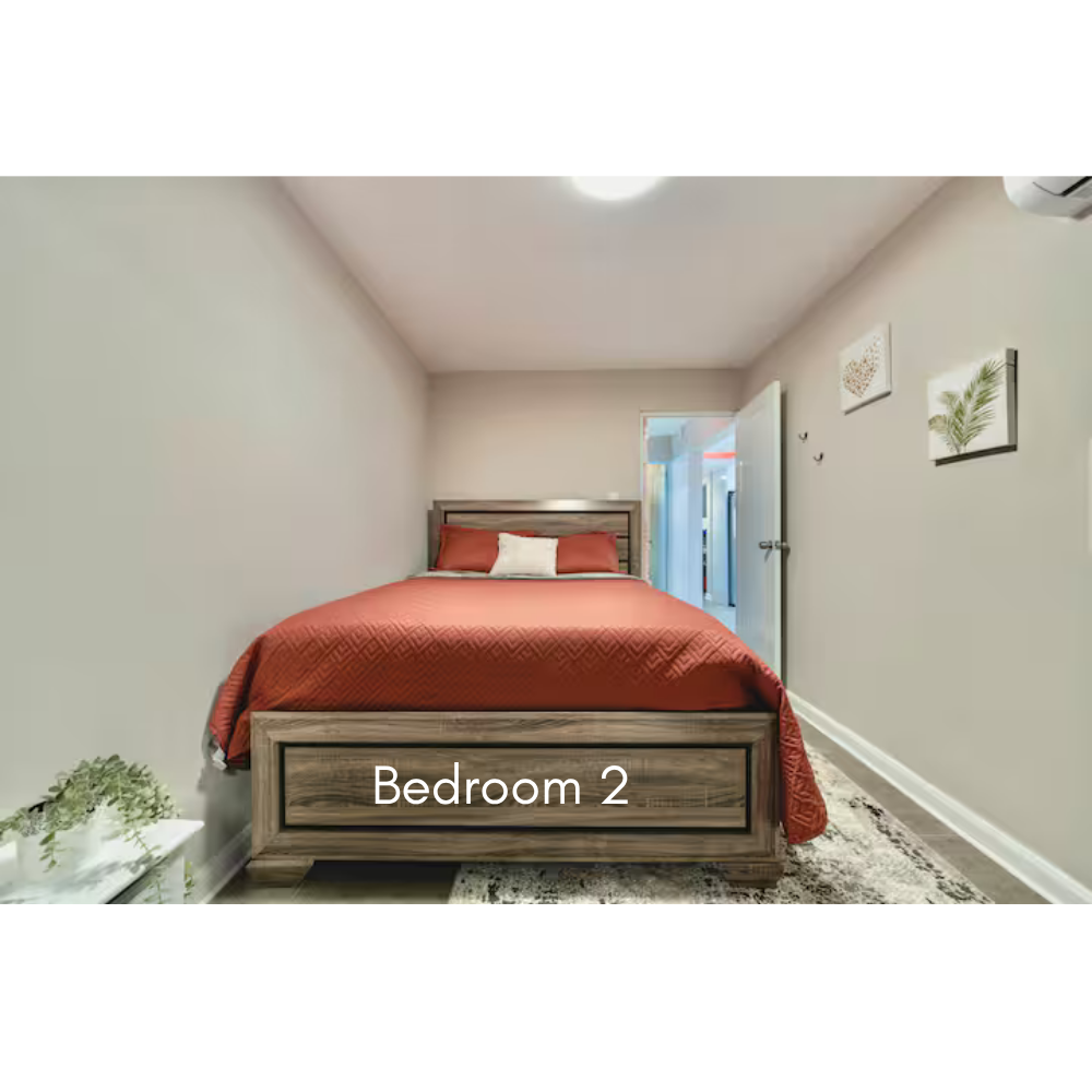 A bedroom with a bed with red bedding and a white pillow, decorated with wall art of leaves and hearts, and labeled 'Bedroom 2'.