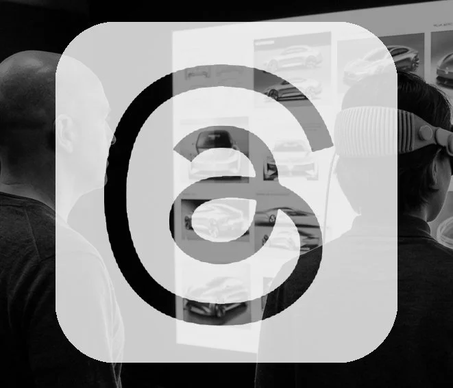 Two people in a room viewing car designs on a wall-mounted display, with virtual reality headset worn by one person.