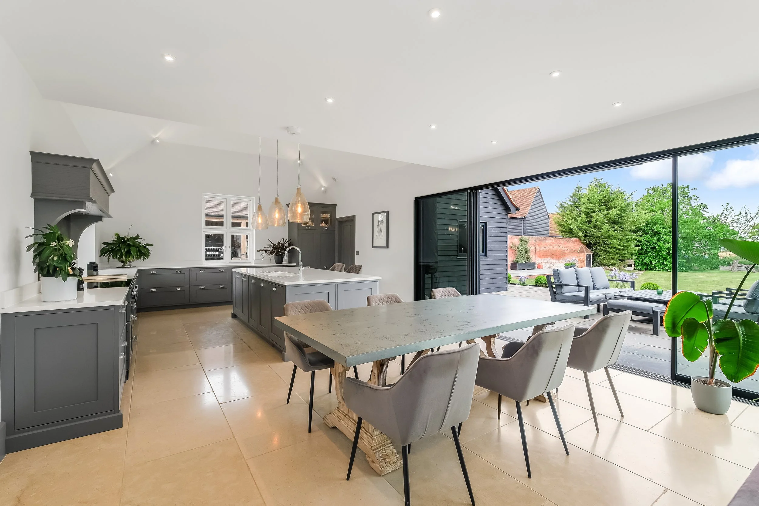 Bright, modern kitchen and dining area with large sliding glass doors opening to a backyard with outdoor seating and lush greenery.