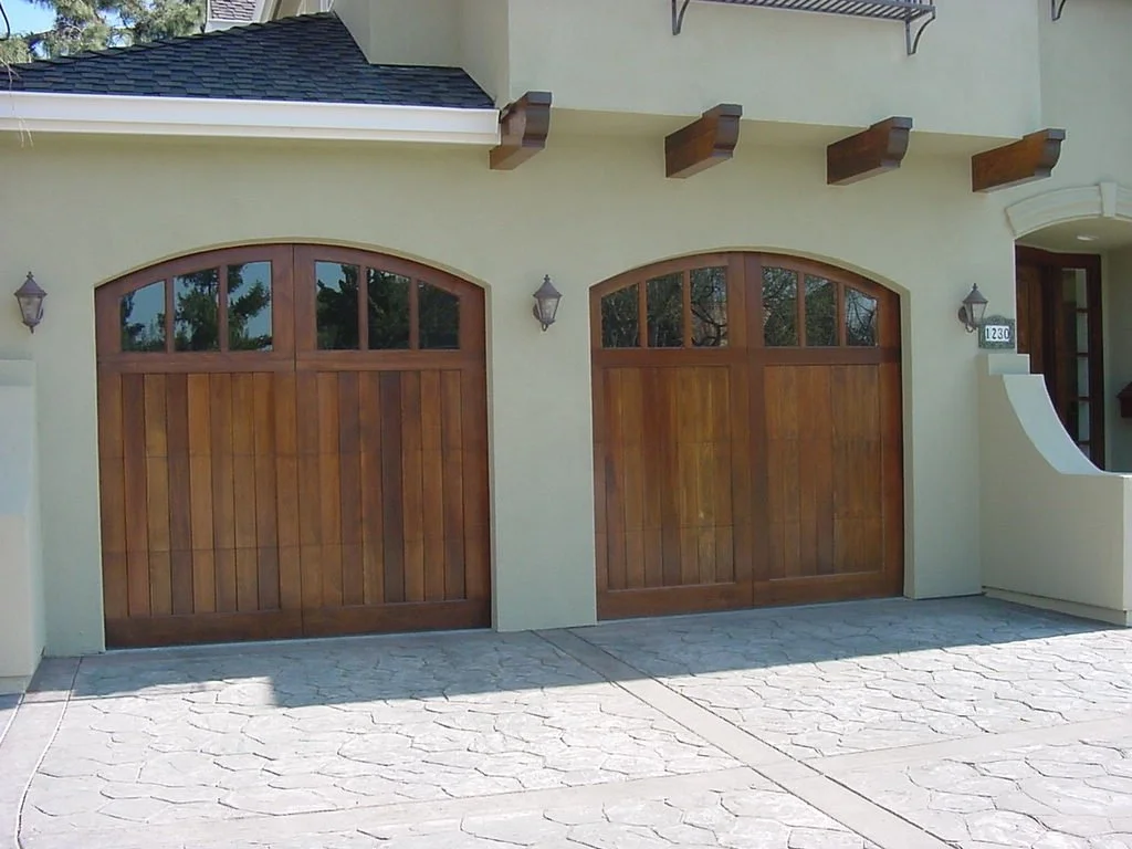 2 1 car wood grain garage doors with arched openings on cream stucco home