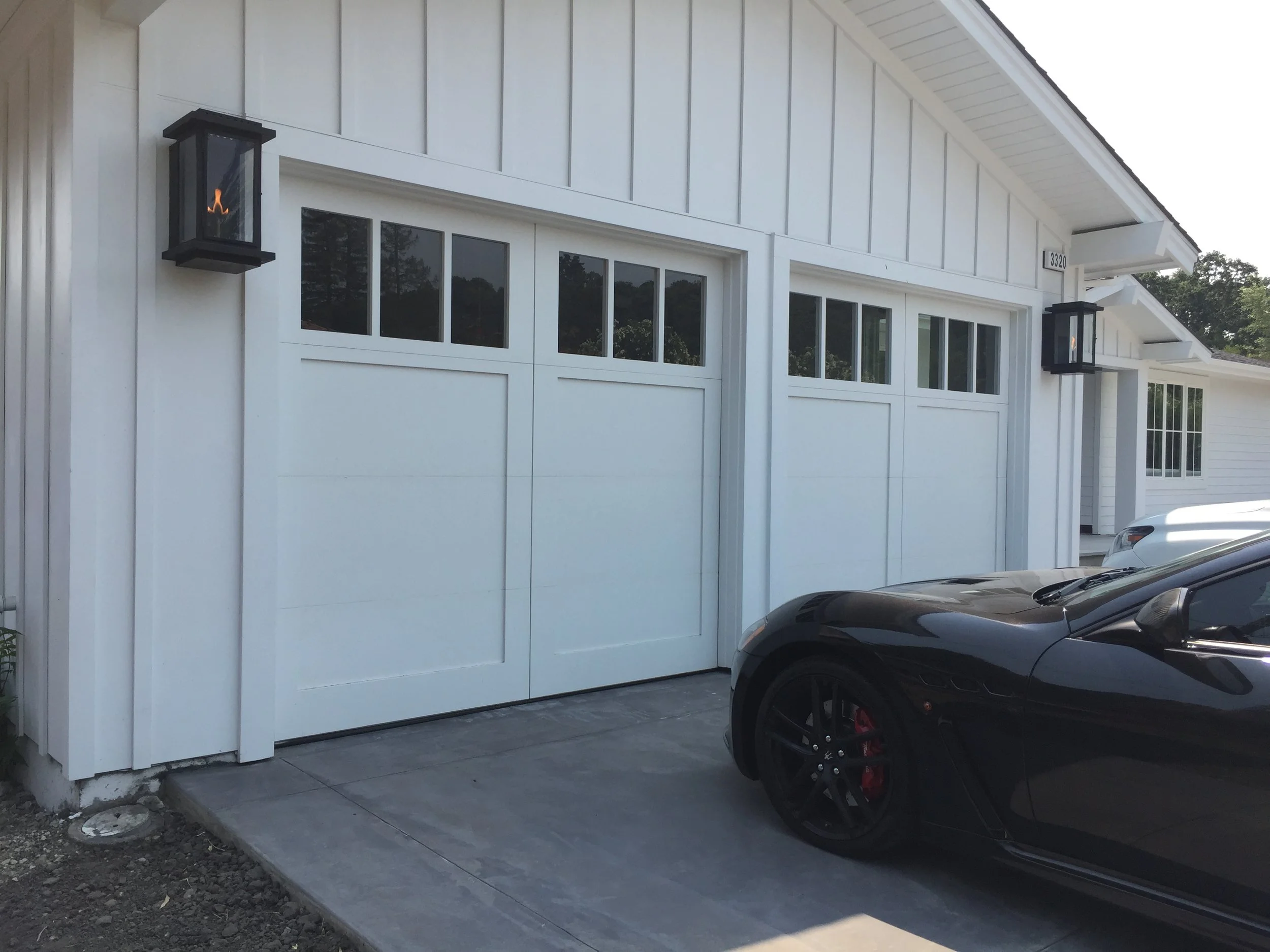 2 1 car wood grain garage doors with arched openings on cream stucco home