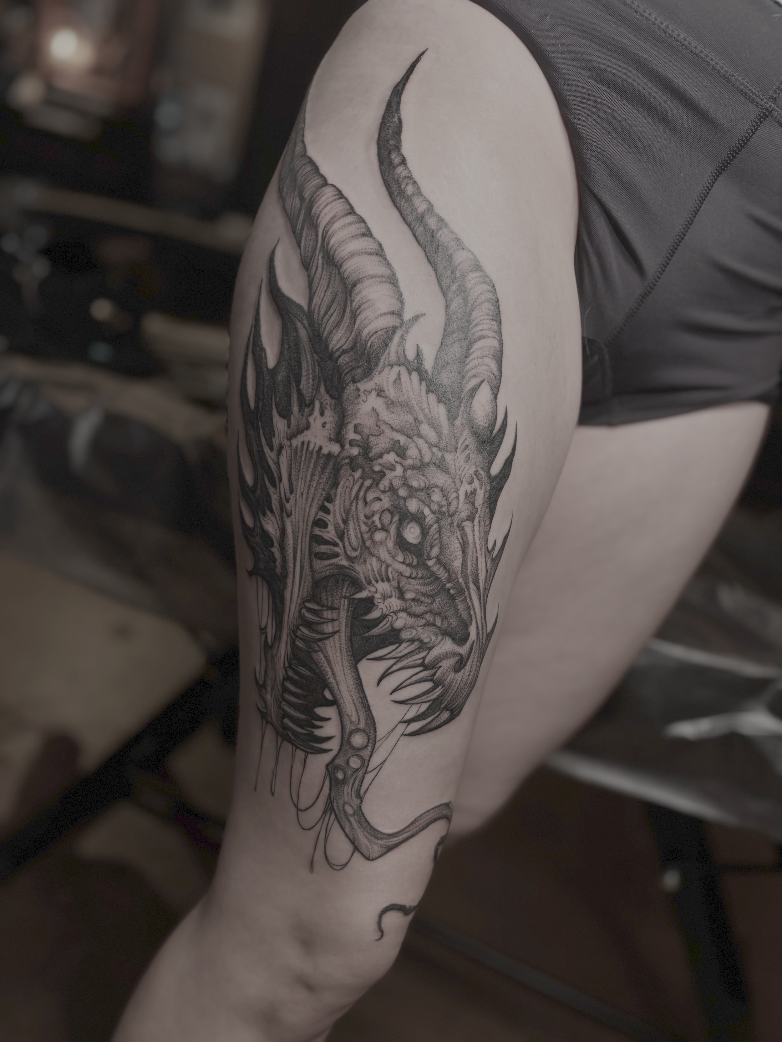 Black and gray tattoo of a dragon on a person's upper arm and shoulder.