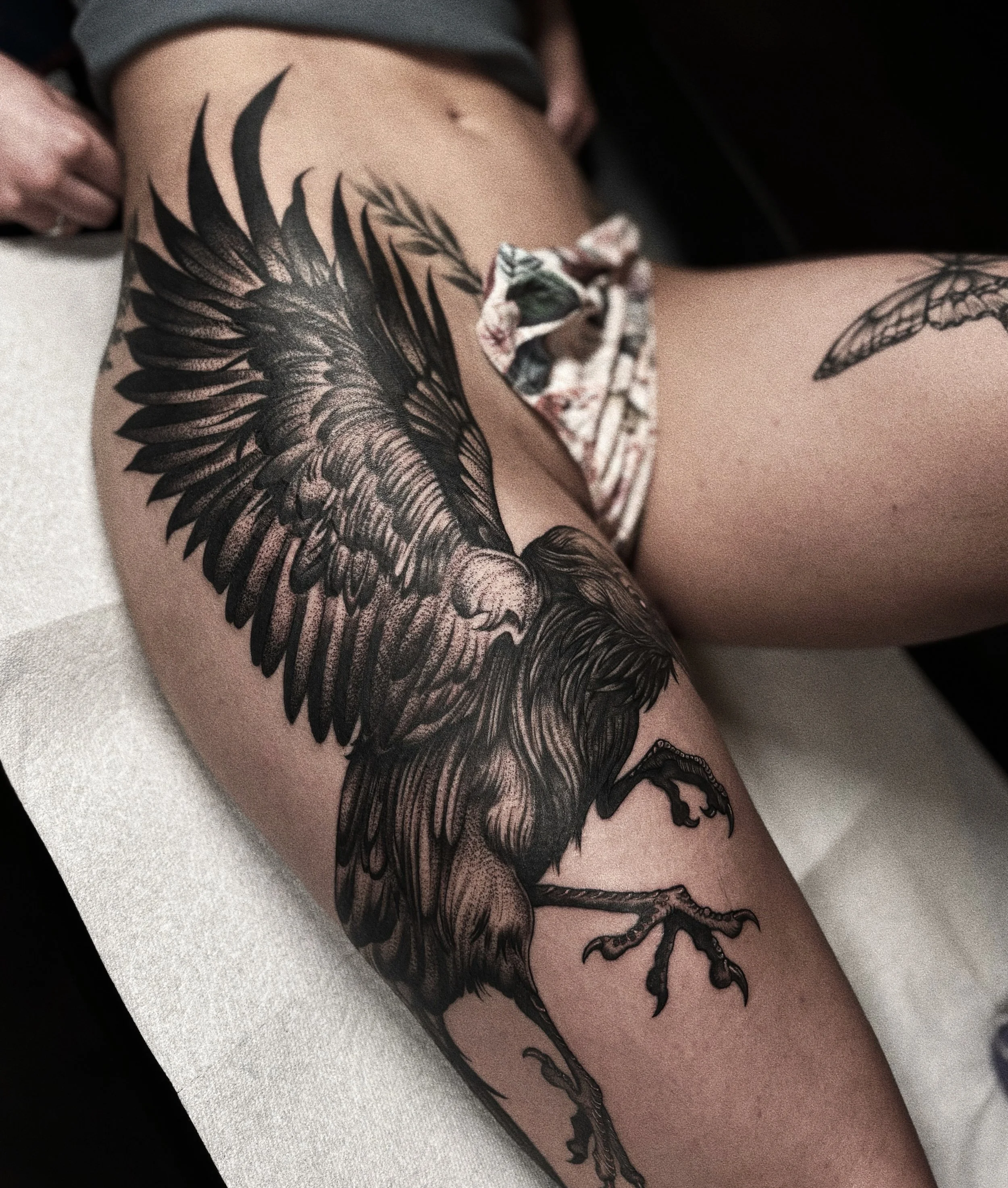 A tattoo of a large, detailed bird with outstretched wings on a person's arm.
