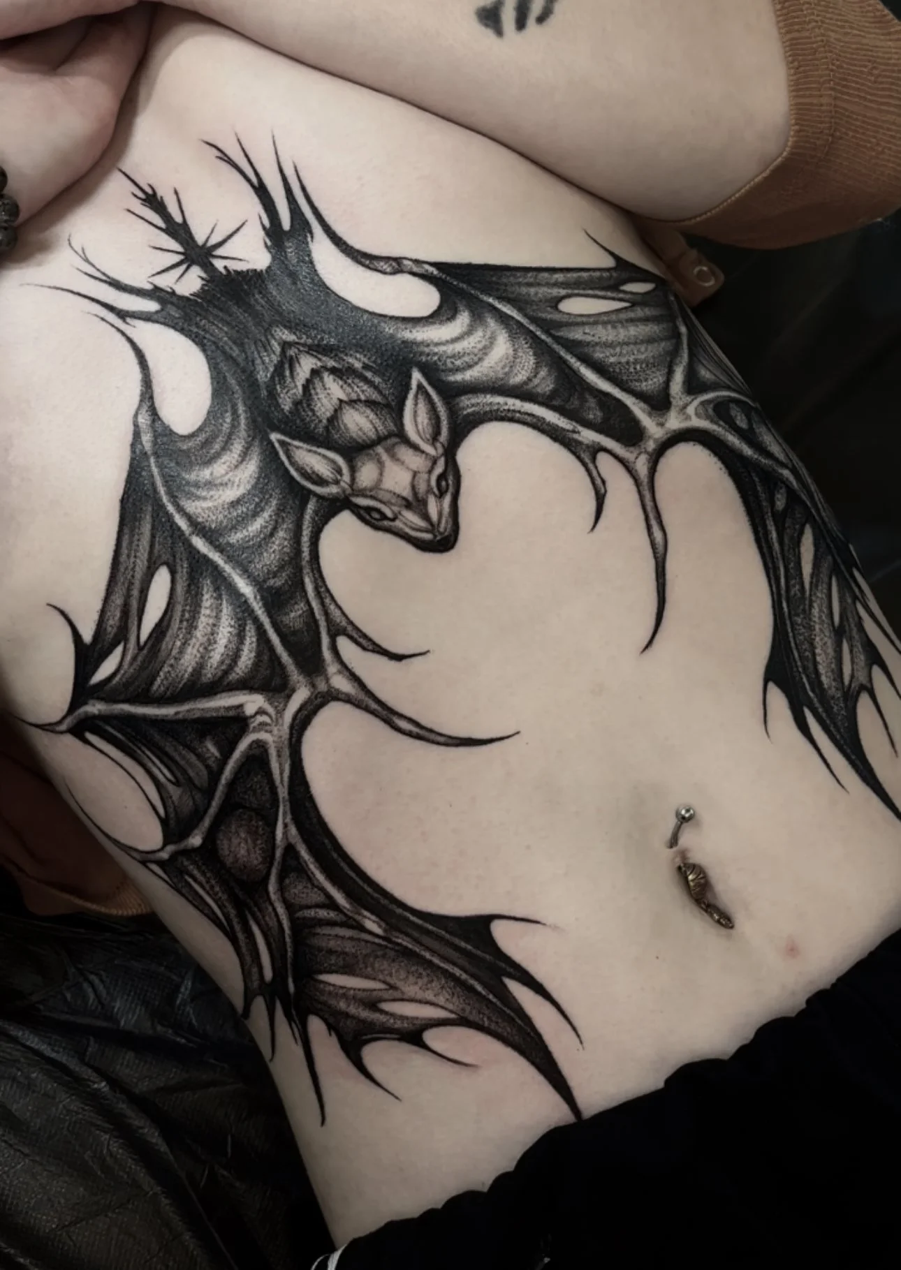 Black and gray tattoo of a deer with large antlers on a person's chest, with a piercing below it.