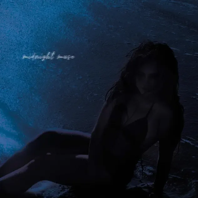 Silhouette of a woman with wet hair sitting on a shoreline at night with dark water in the background.
