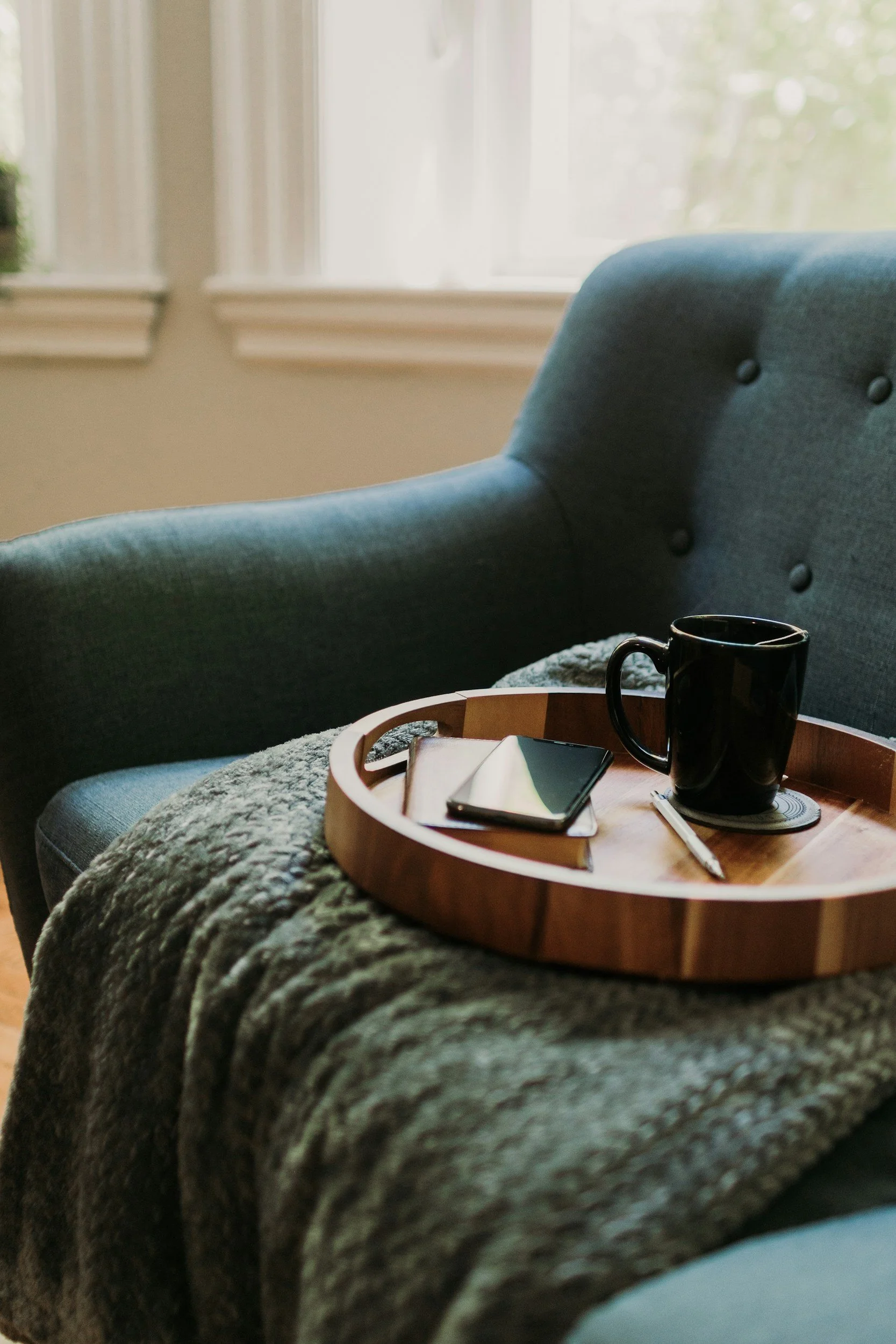 Teal armchair, green blanket, round tray with journals and tea.Coping skills.