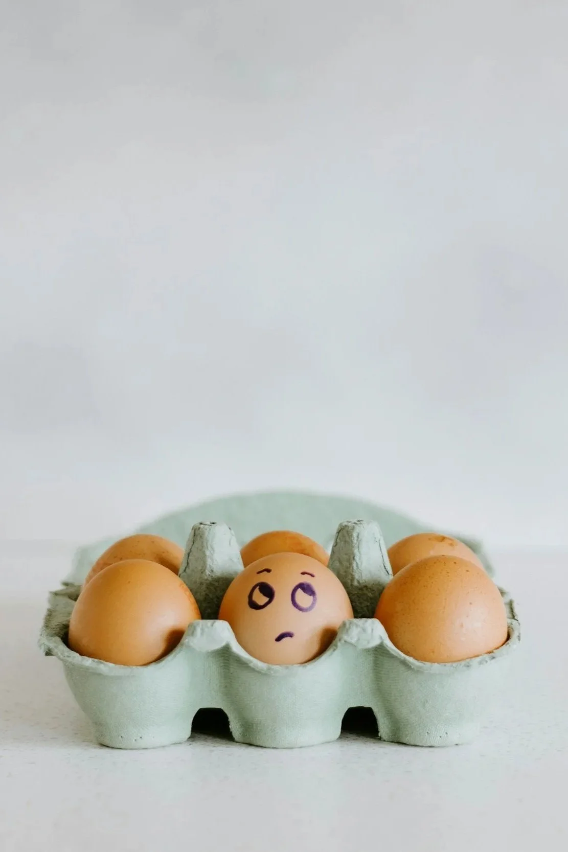 Egg in a carton with a concerned face drawn on it to symbolize disordered eating.