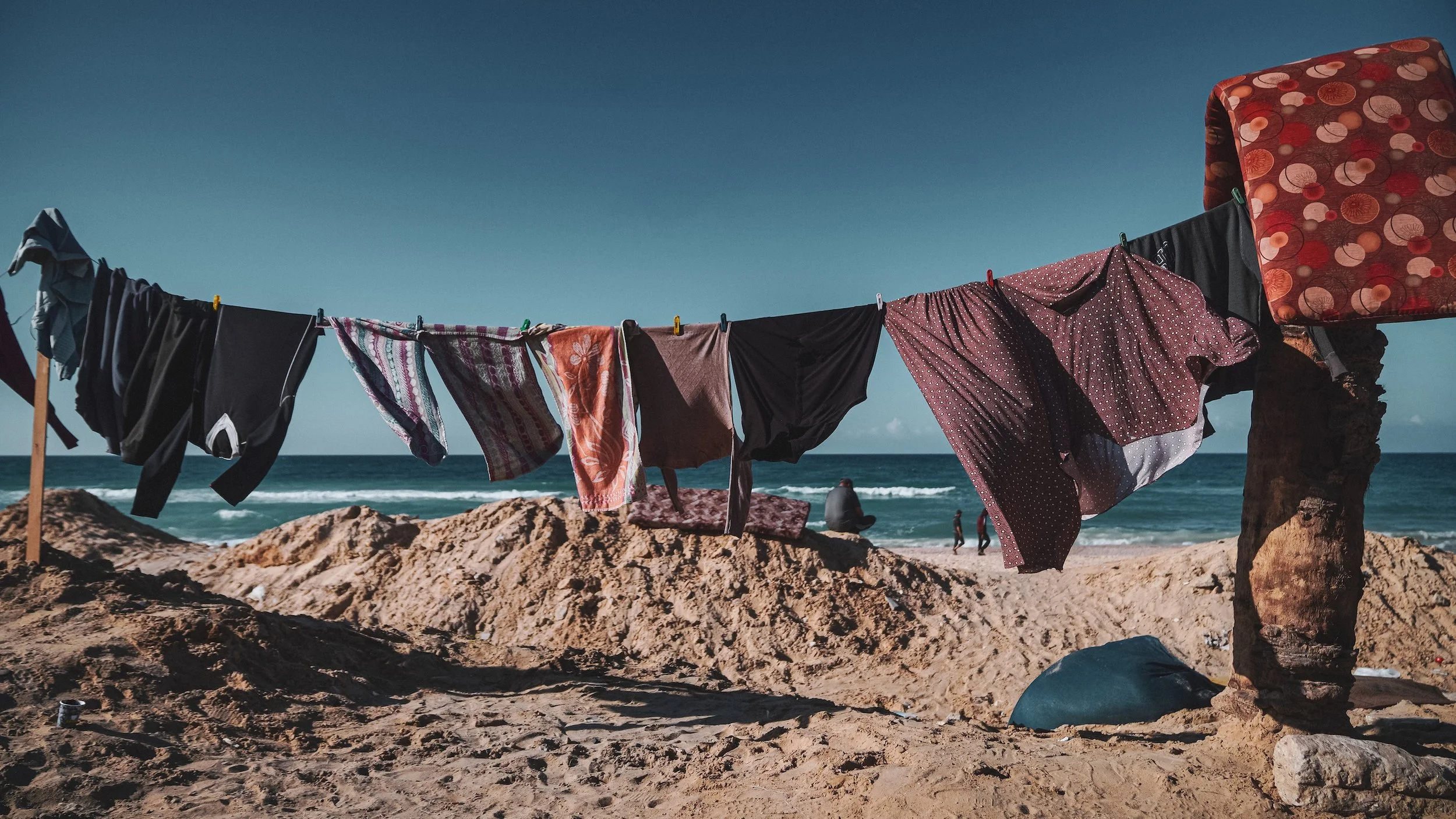 Clothes hanging on a clothesline at the beach in Gaza, with the ocean in the background.