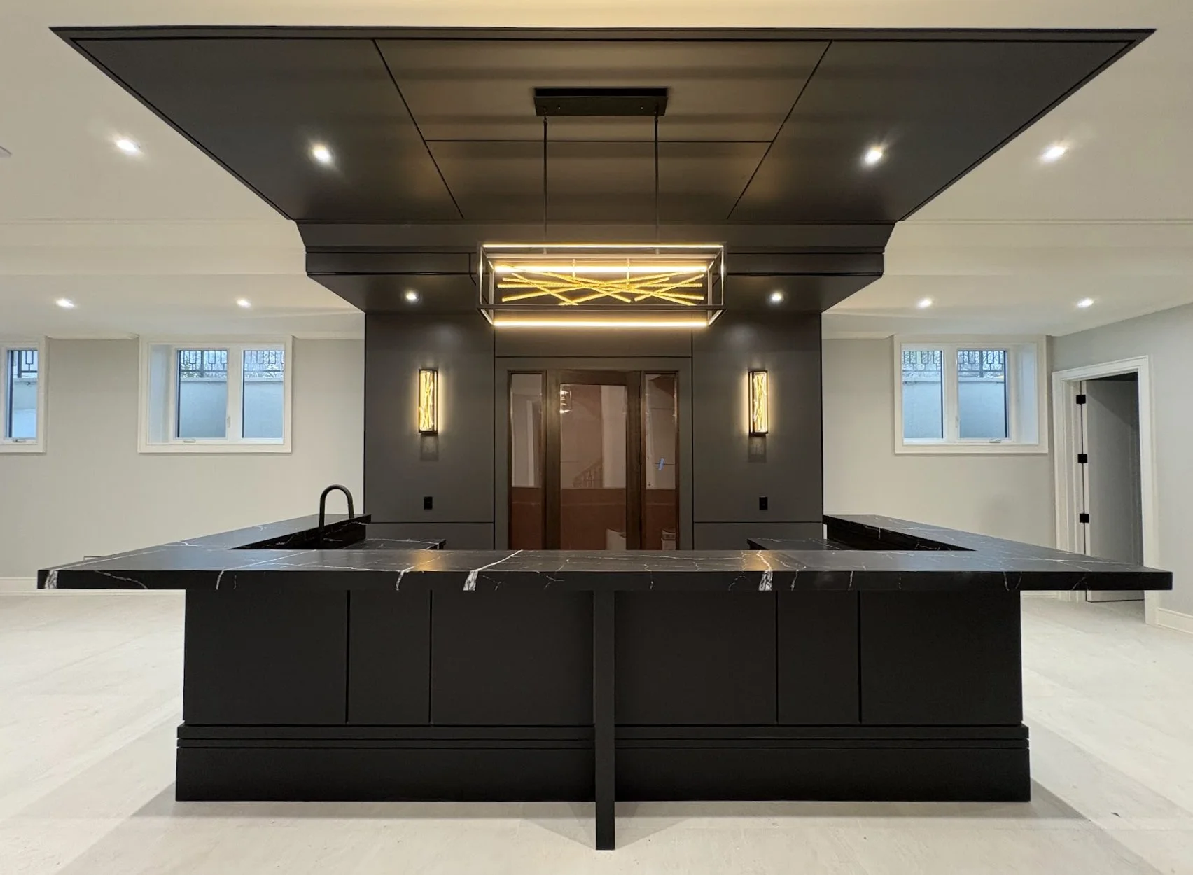 Modern kitchen with black marble island, black cabinets, and decorative lighting fixture hanging from a black ceiling