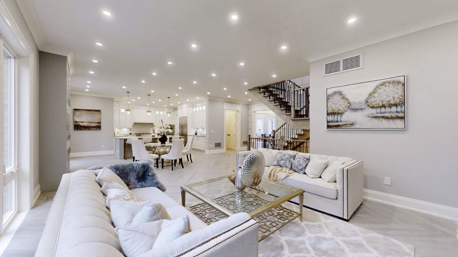 Bright open-concept living room and kitchen with white furniture and modern decor.