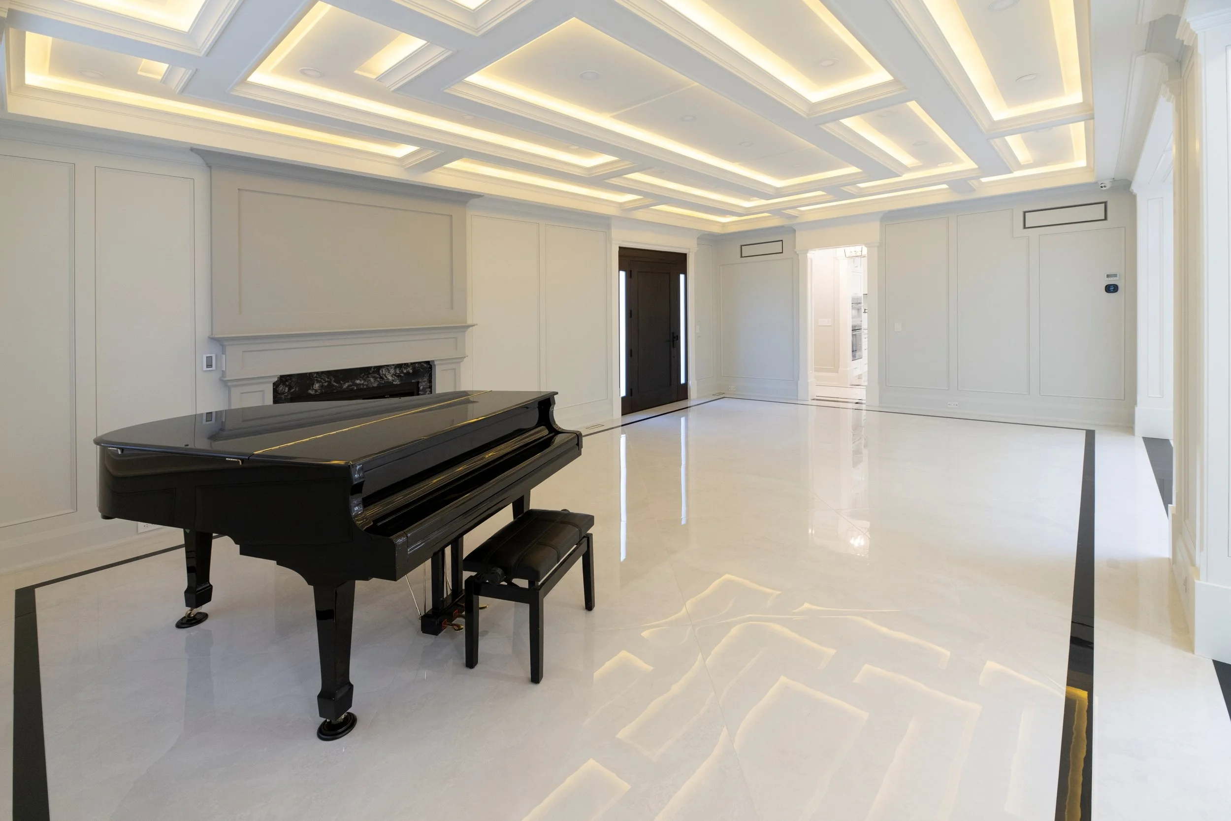 Empty living room with a black grand piano, white walls with molding, marble flooring, and a modern ceiling with recessed lighting.