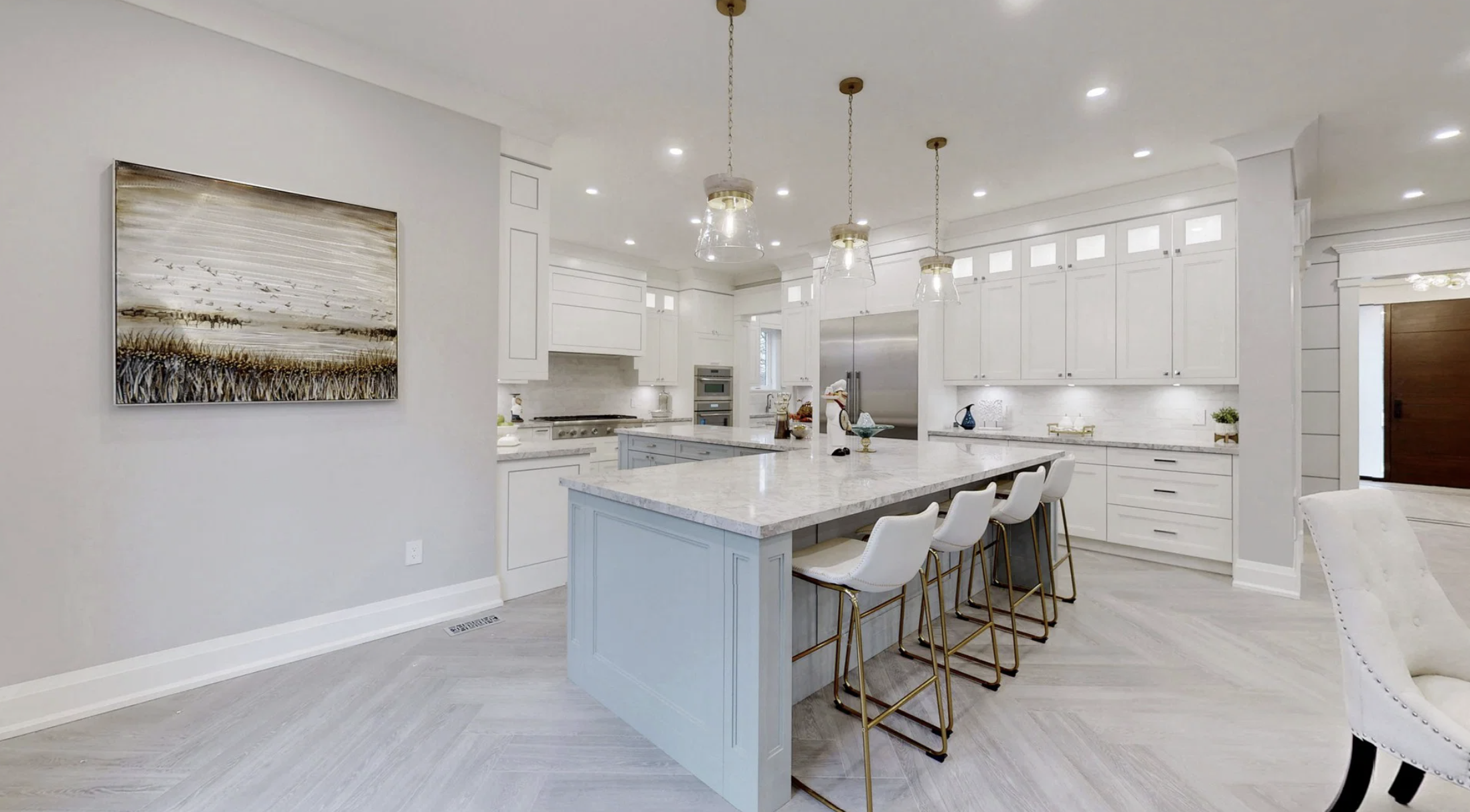 Modern white kitchen with an island, pendant lights, and white bar stools.