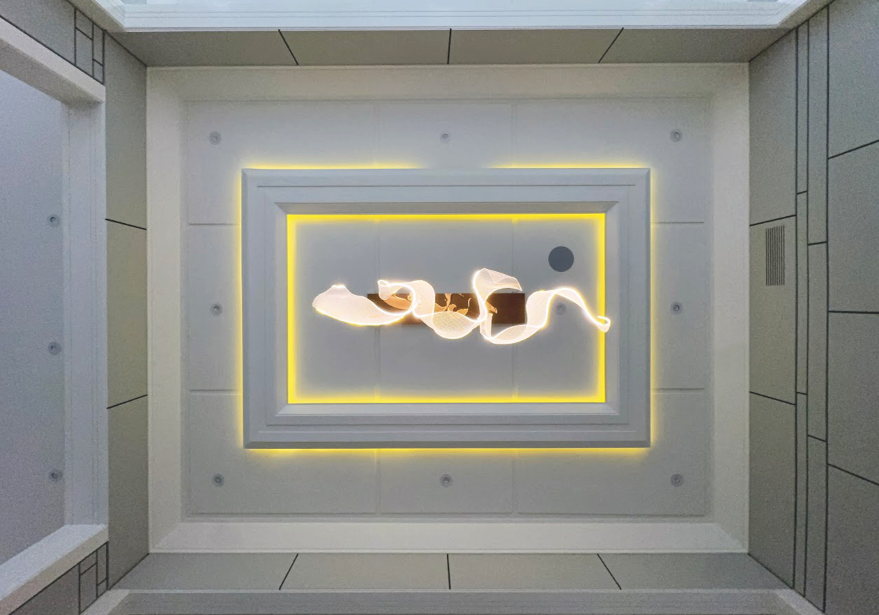 A ceiling with a modern square chandelier featuring a glowing yellow frame and a twisting white light fixture in the center.