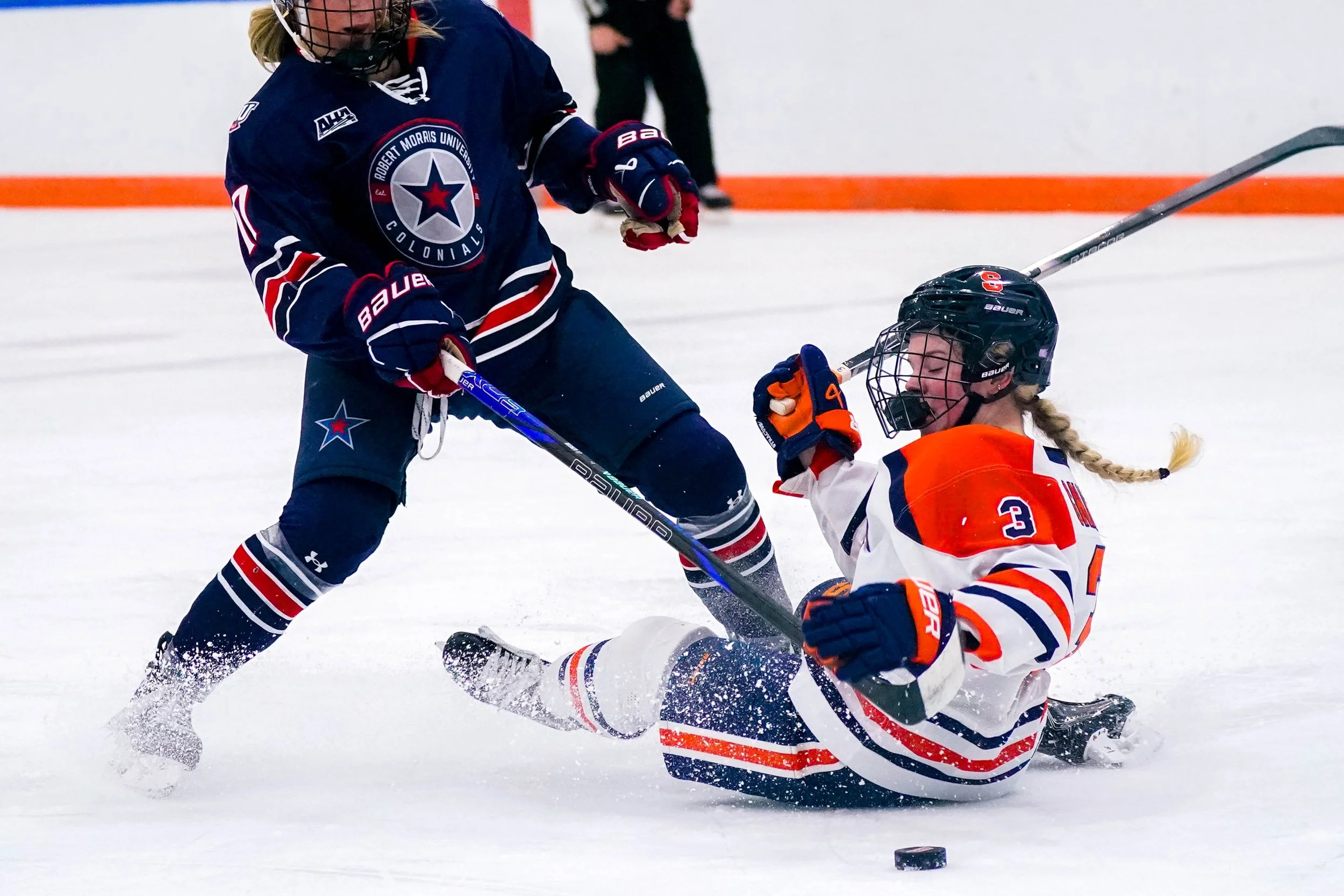Syracuses Emma Gnade #3 falls to block Robert Morris University player from stealing puck during womens ice hockey game in Tennity Ice Skating Pavilion. Photo by Emily Hoban.