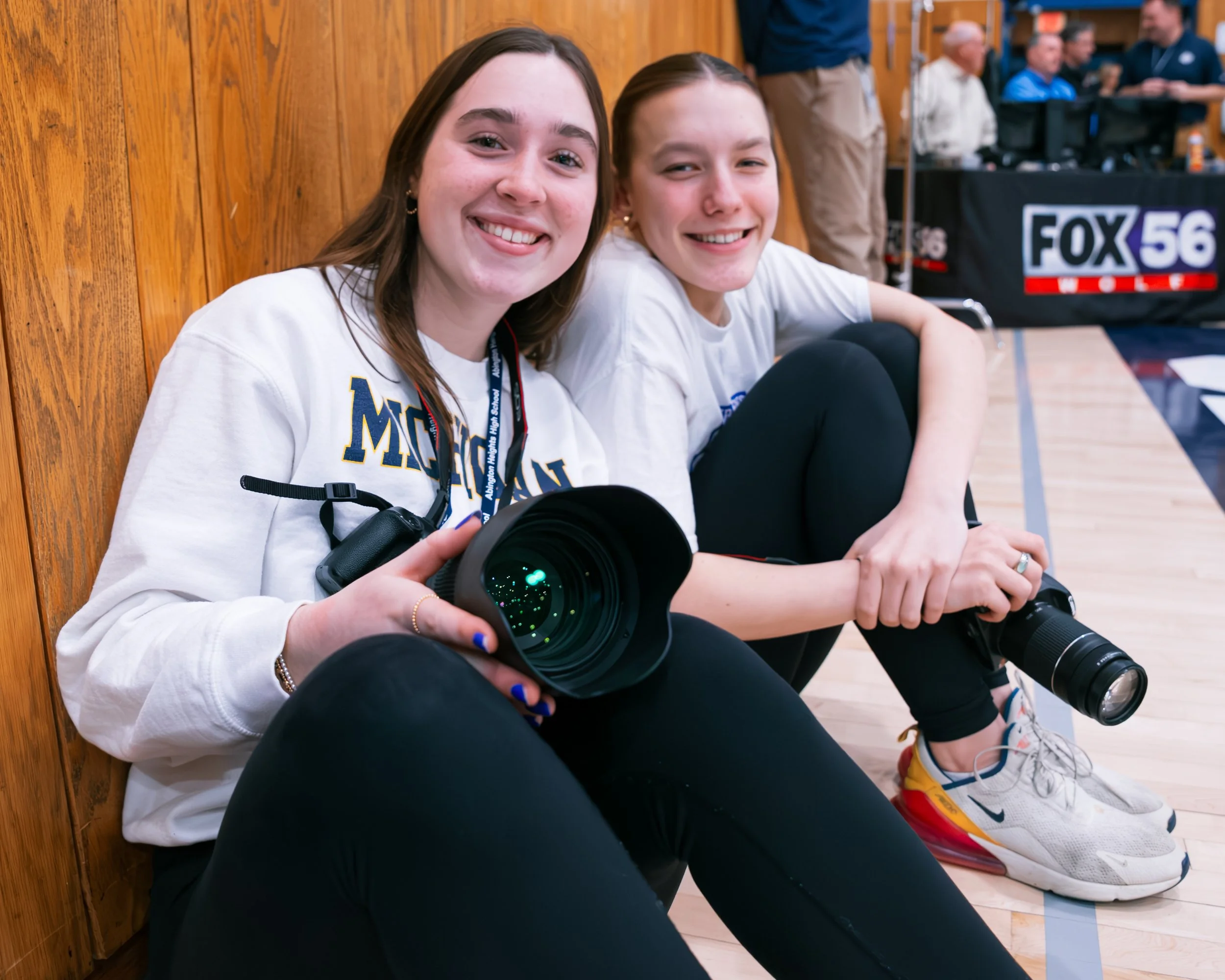Emily Hoban is sitting alongside photographers courtside at a basketball game.