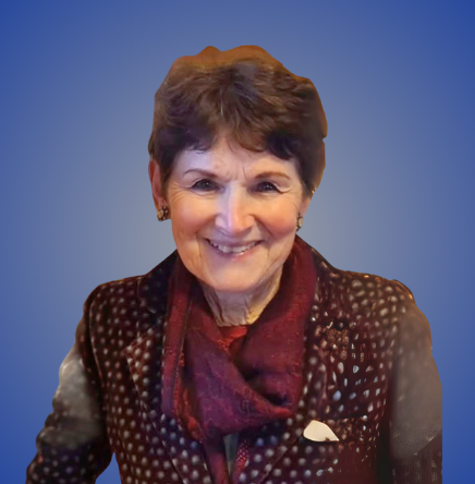 A smiling woman with short brown hair, wearing a dark polka-dotted blazer and a red scarf, against a blue background.