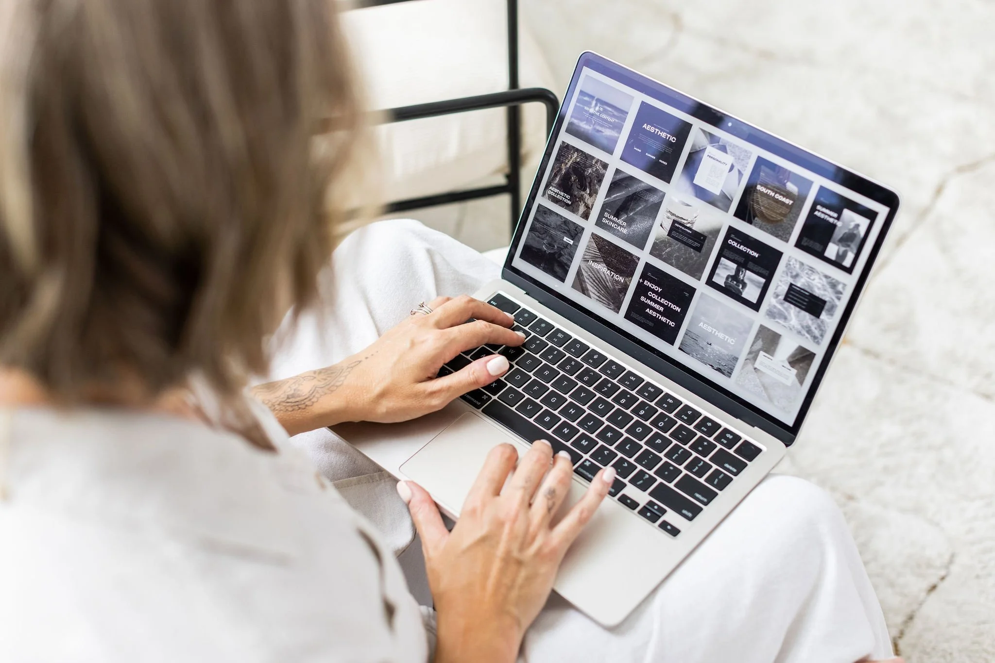 Person using a laptop with a webpage display showing a grid of black and white images and text.