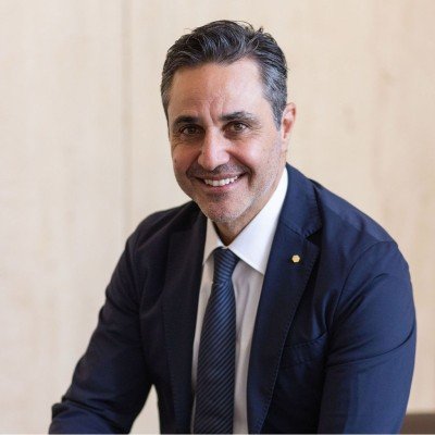 Sandro Razzi from Core engineering. A man wearing a navy suit with a white shirt and tie, smiling in front of a plain background.