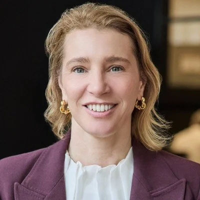 Florencia Tarelli from The Powerful Brand Group. A smiling woman with blonde hair wearing a purple blazer and gold earrings.