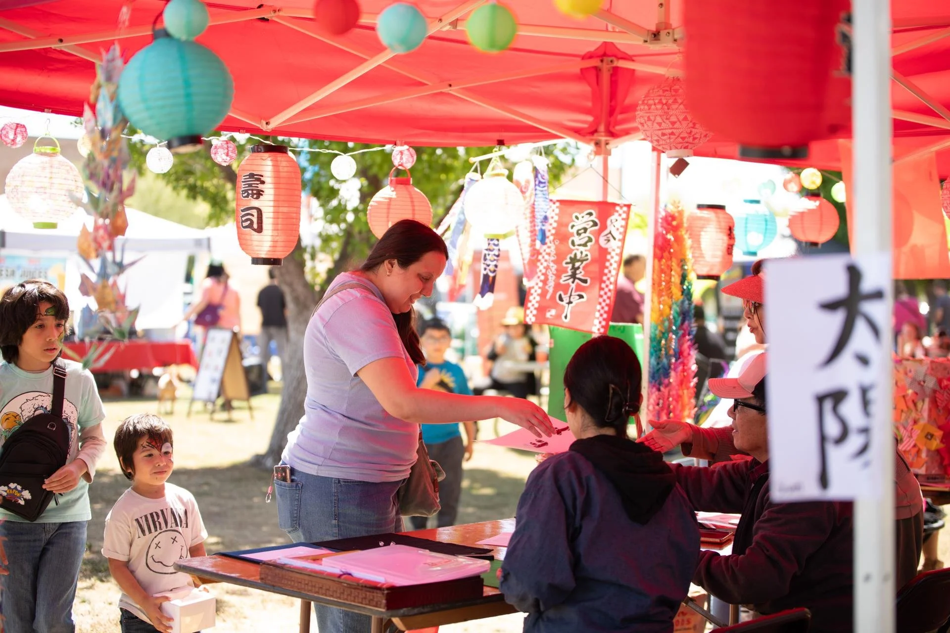 A woman at an event fair reaches over to the artwork on display.